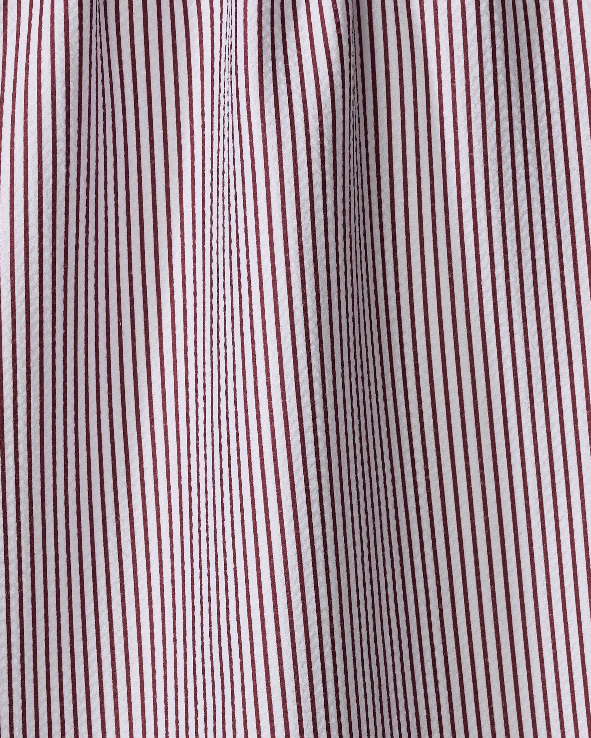 Close-up of The Buy Guide's Get In Line - Wine tea towel, featuring vertical maroon pinstripes on white cotton, a textured and slightly wrinkled surface, and gathered detailing at the top.