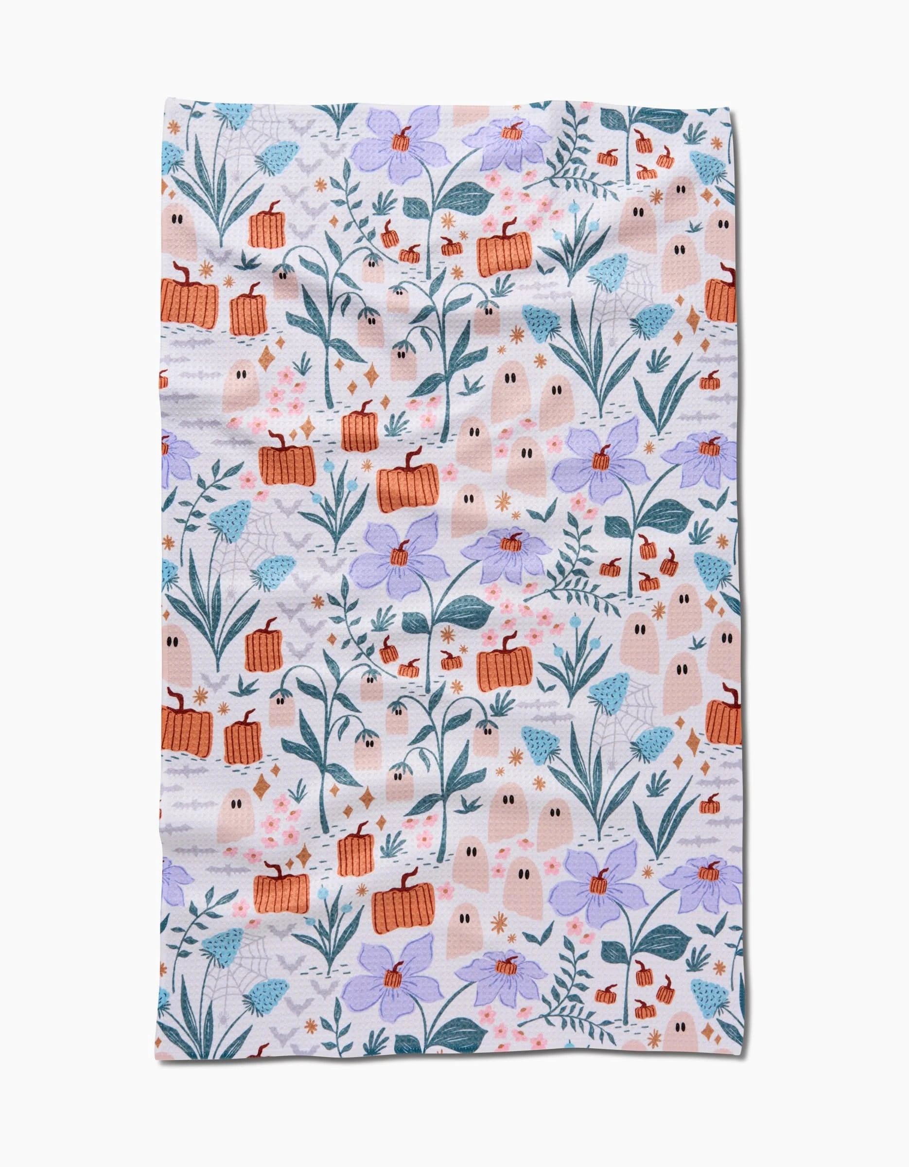The Ghosts In The Garden tea towel by Charlie Rowan Designs is crafted from recycled materials and features orange baskets, white ghosts, red mushrooms, and purple flowers with green leaves on a light background.