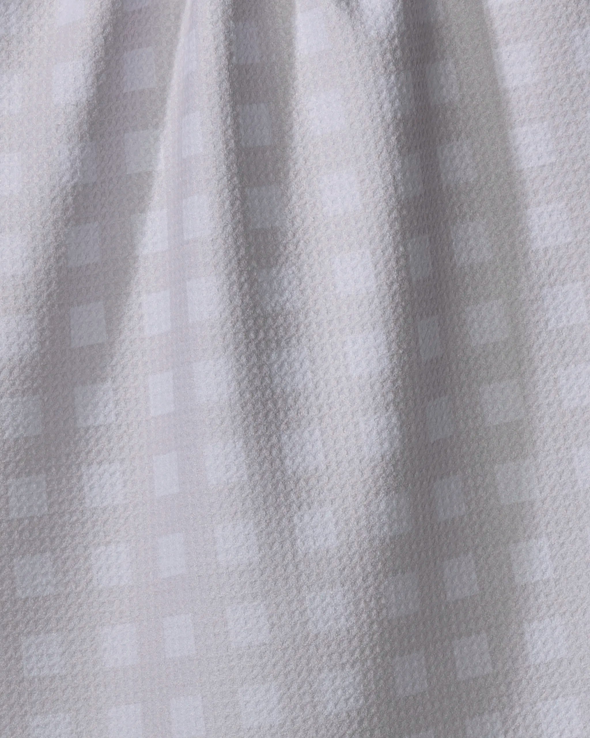 A close-up of Gigi - Beige by The Buy Guide, featuring light beige recycled fabric with a subtle checkered pattern and gently textured surface—ideal as a kitchen towel, displayed with soft vertical folds.
