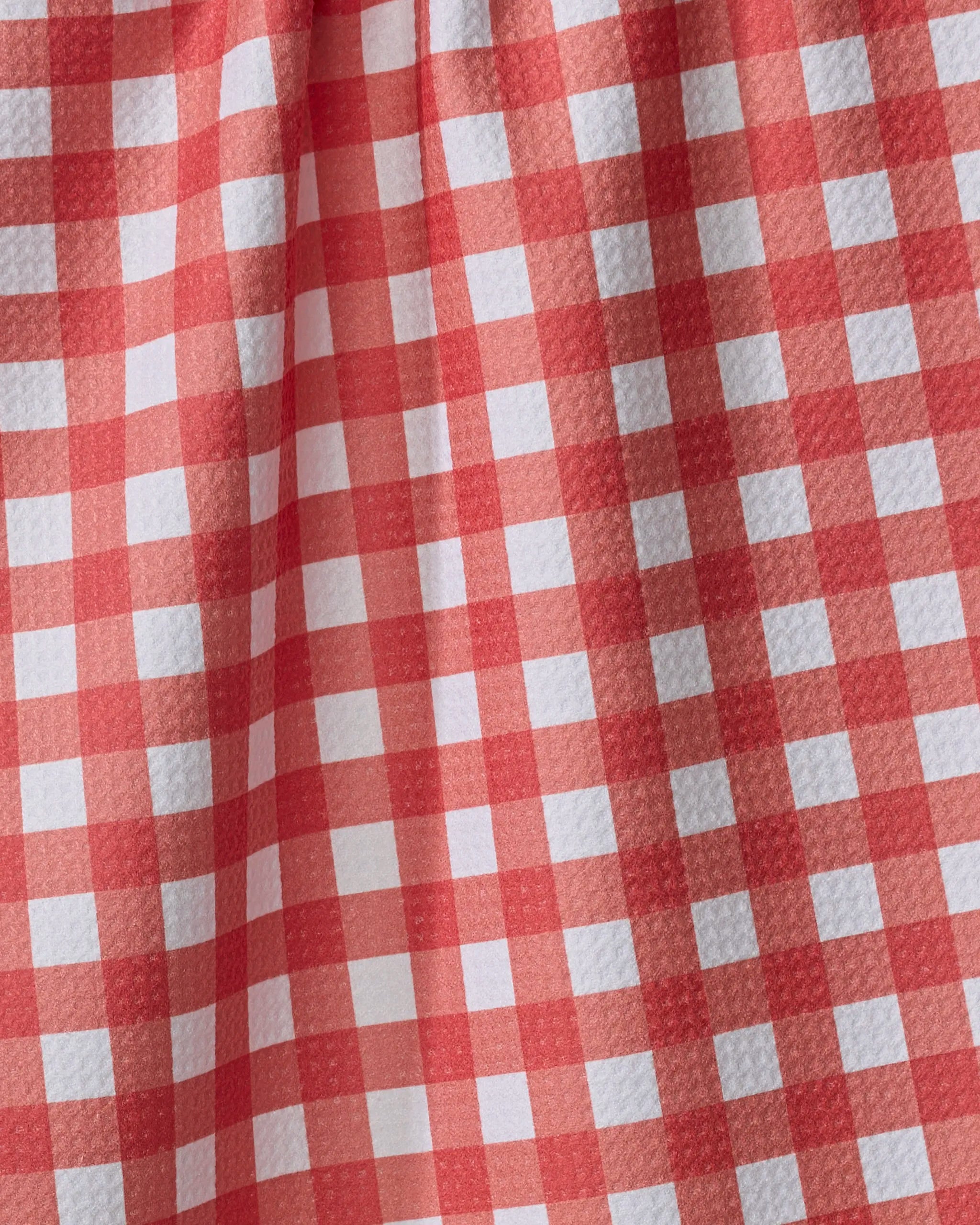 The Buy Guide's Gigi - Candy Apple features a textured red and white gingham fabric with folds that create unique shadows—ideal for use as an eco-friendly kitchen towel.