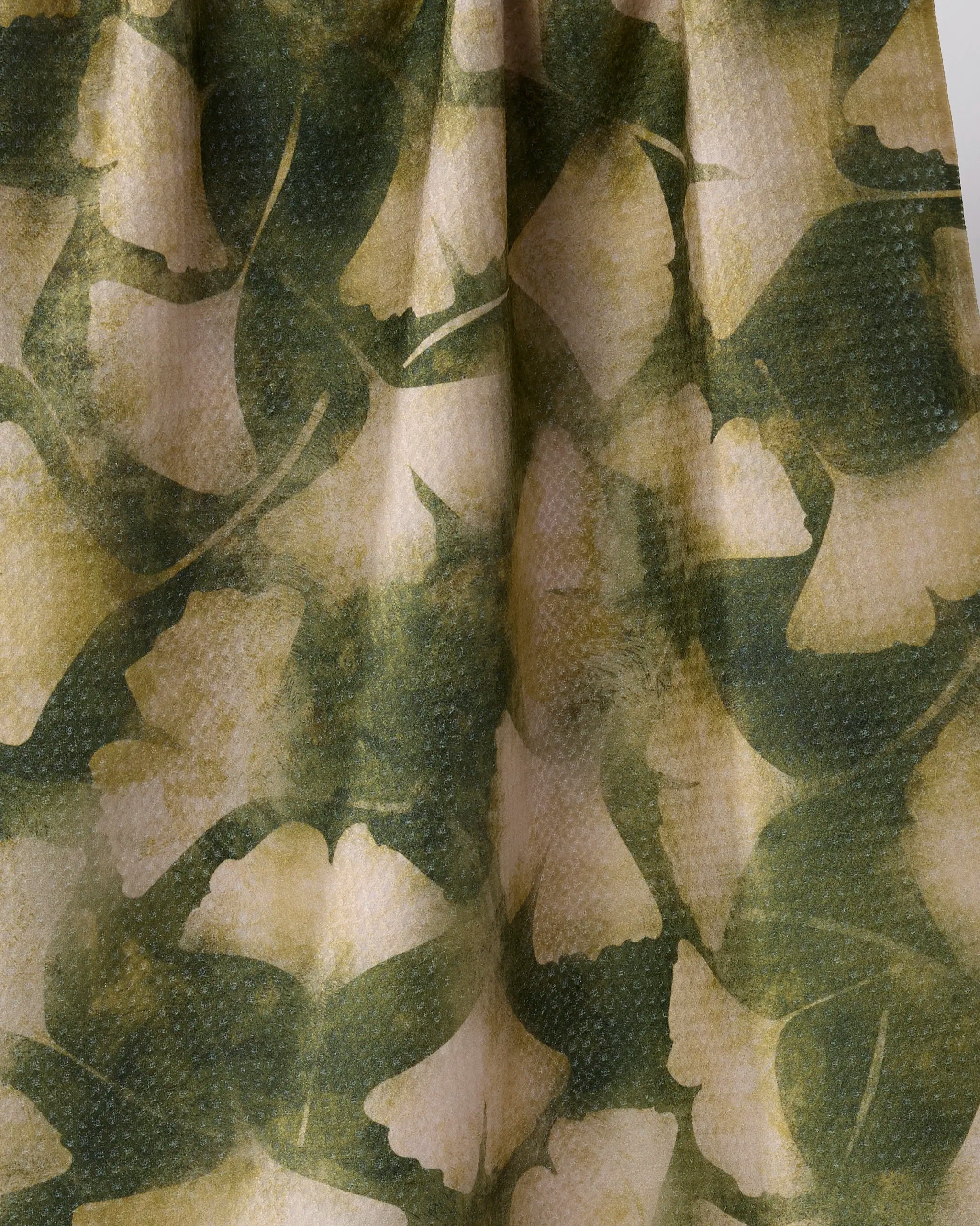 Close-up of Geometry's Gilded Ginkgo recycled kitchen towel, displaying a green and beige leafy ginkgo pattern with overlapping shades of green for a natural, textured look.