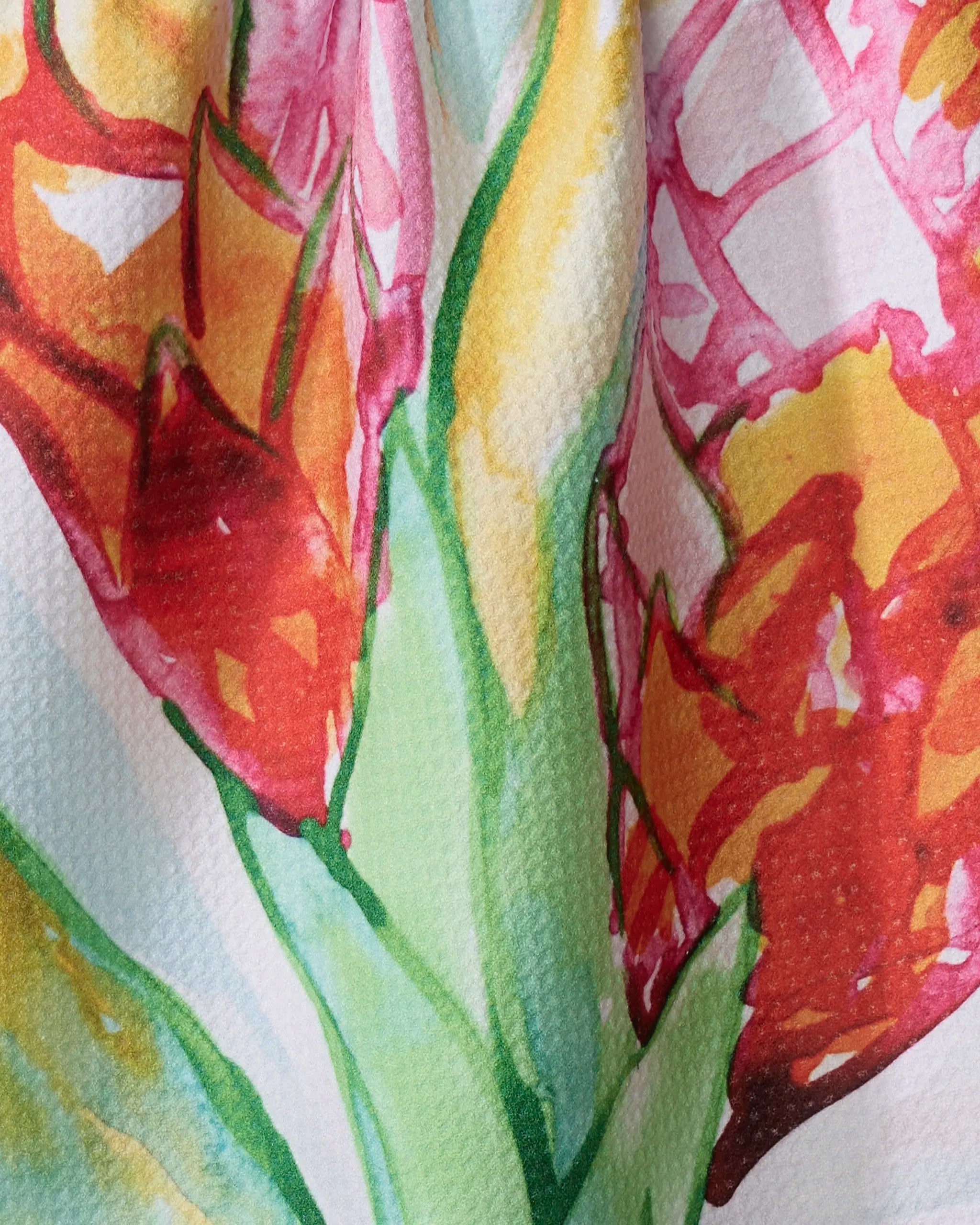 Close-up of the “Ginger” kitchen towel by Skye Walker, featuring a vibrant floral pattern with red and yellow tulips, green leaves, and textured watercolor-style brushstrokes. Eco-friendly and colorful.