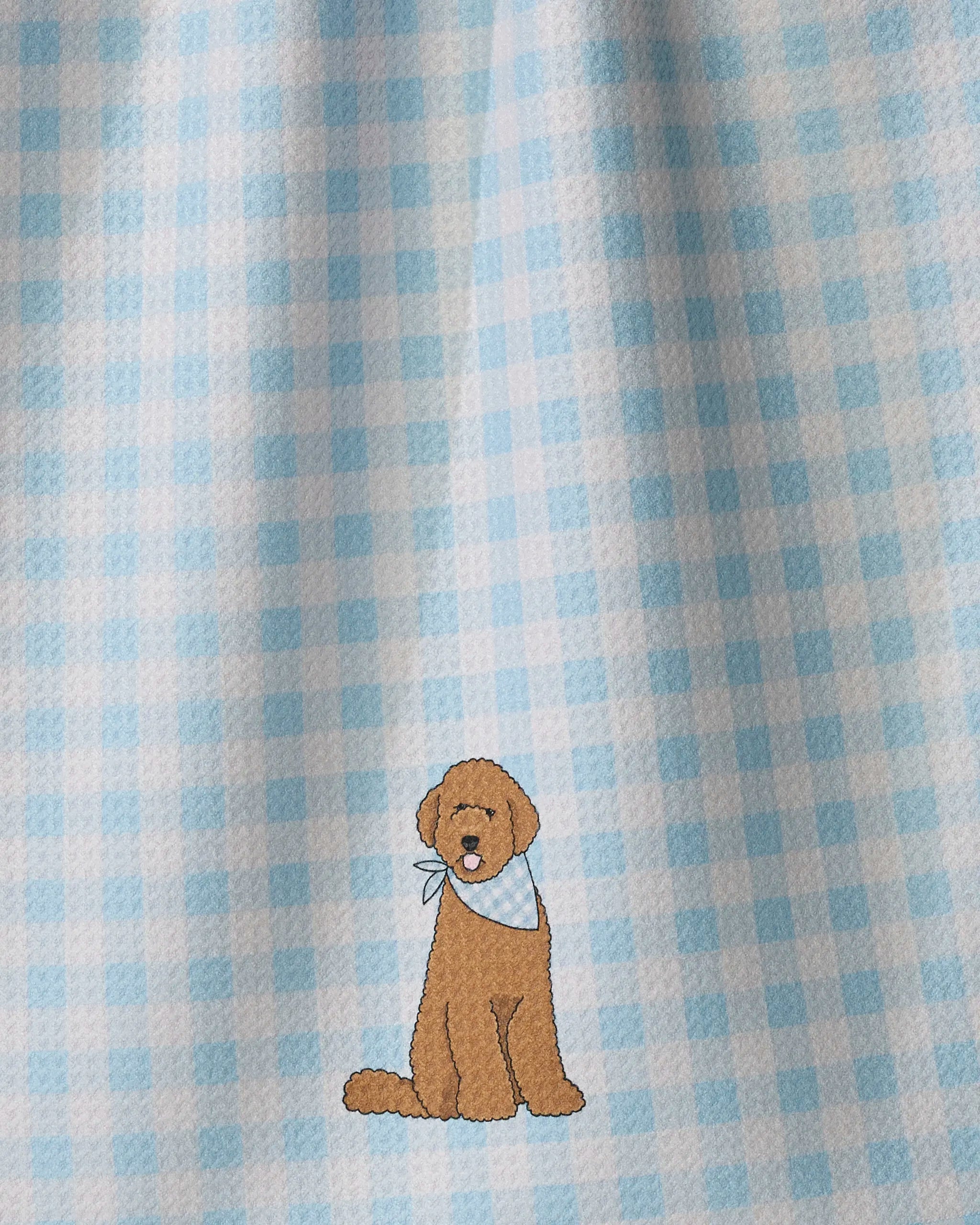 A cartoon brown dog wearing a blue bandana sits on a blue and white Gingham Doodle by Geometry, its charming tea towel design made from ultra-absorbent recycled materials.