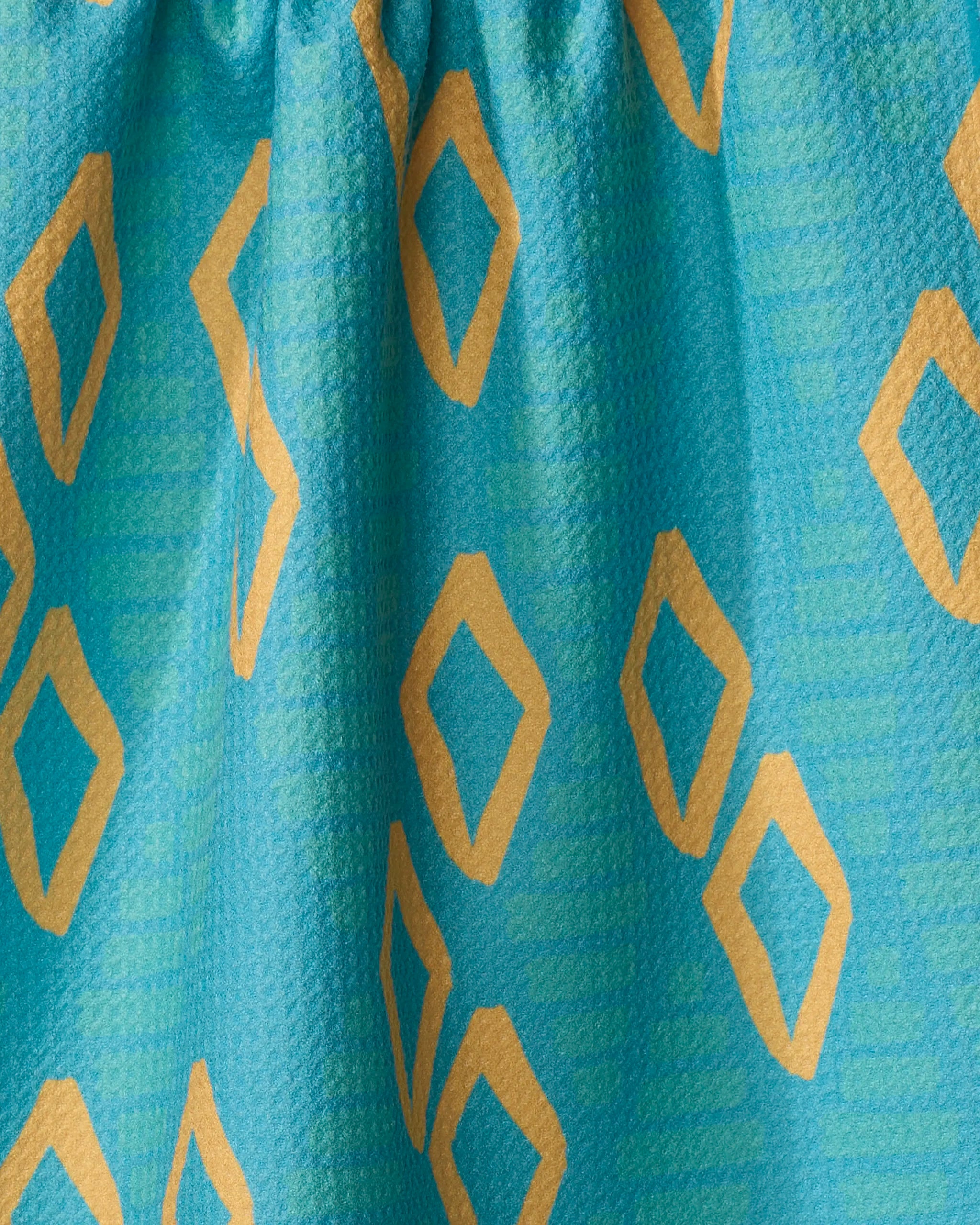 A close-up of Girl's Best Friend by Sareka Unique shows teal eco-friendly tea towel fabric with a textured surface and scattered yellow diamond shapes. The kitchen towel is slightly gathered at the top.