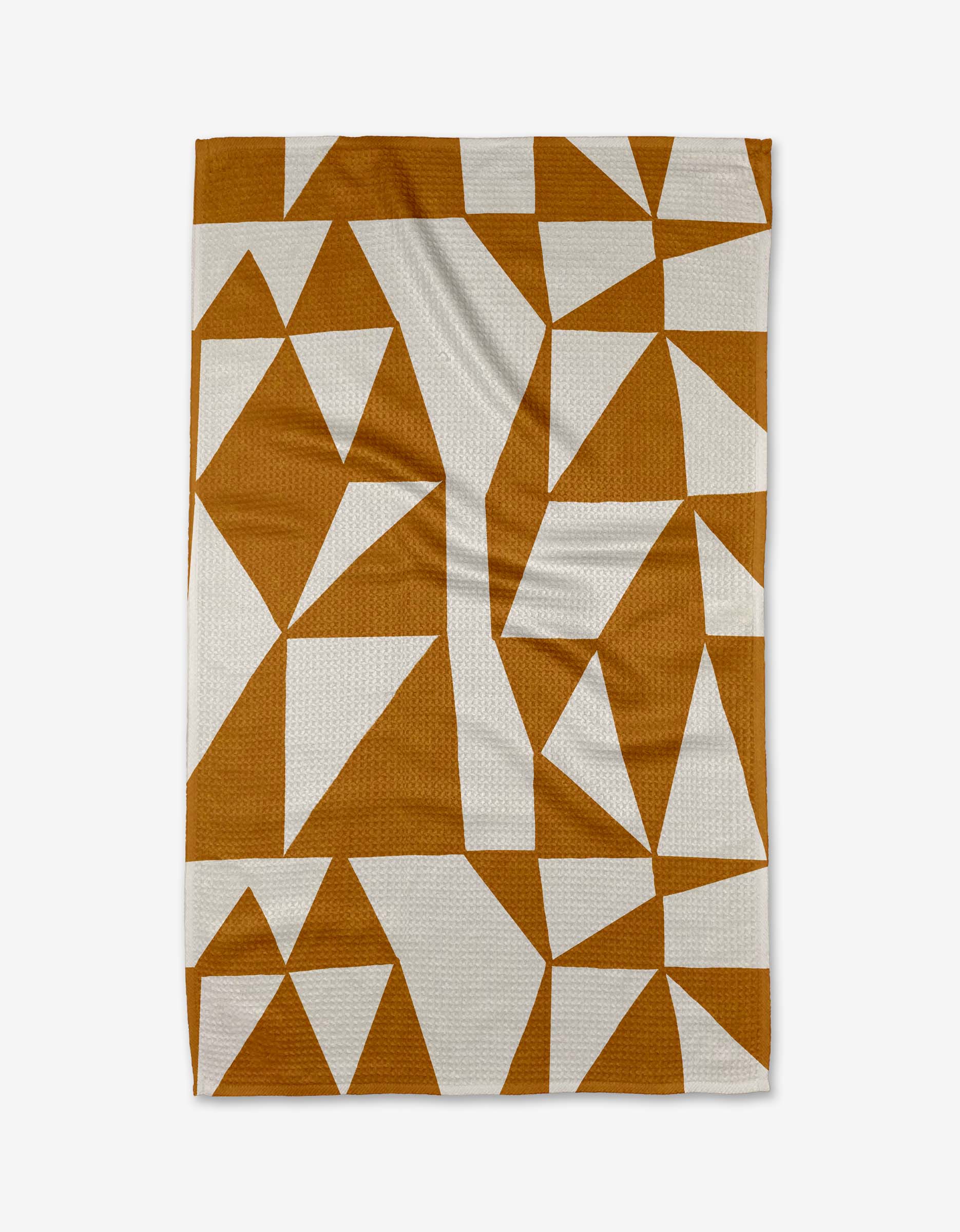 The Golden Angles blanket by Lisa Nelson is rectangular, made from recycled materials, and showcases a geometric pattern of brown and white triangles and polygons on a flat surface.