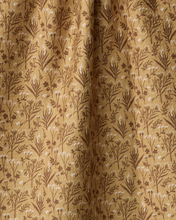 The Golden Fall Flowers tea towel by Danelys Sidron features a detailed botanical pattern in golden brown shades. Made from ultra-absorbent recycled materials, it has a soft texture and gentle folds for added elegance.