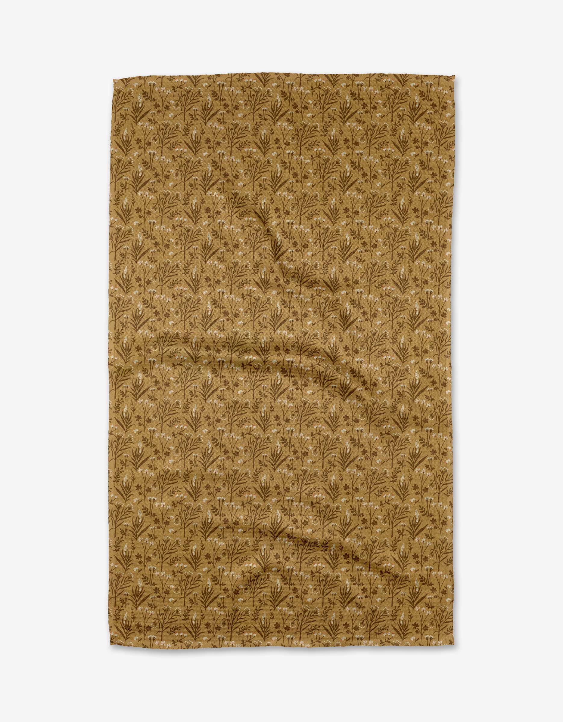 The Golden Fall Flowers tea towel by Danelys Sidron is a rectangular, brown cloth made from recycled materials, featuring a repeating botanical pattern of small leaves and branches. It is slightly wrinkled and shown on a white background.
