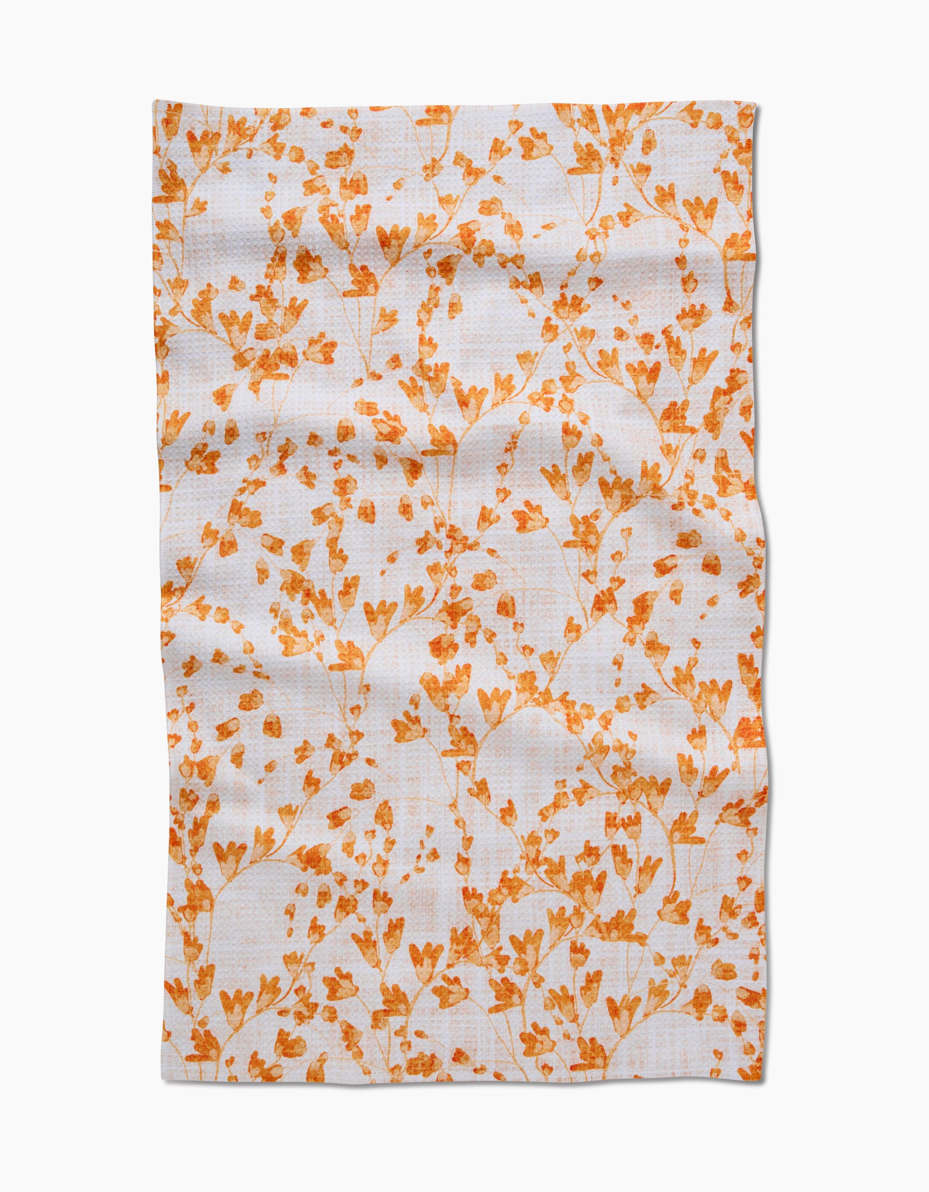 The Golden Grassland tea towel by Pascale Dilger features white Geoweave™ fabric textured with small orange flowers and delicate branches, shown slightly wrinkled and spread out on a plain background.