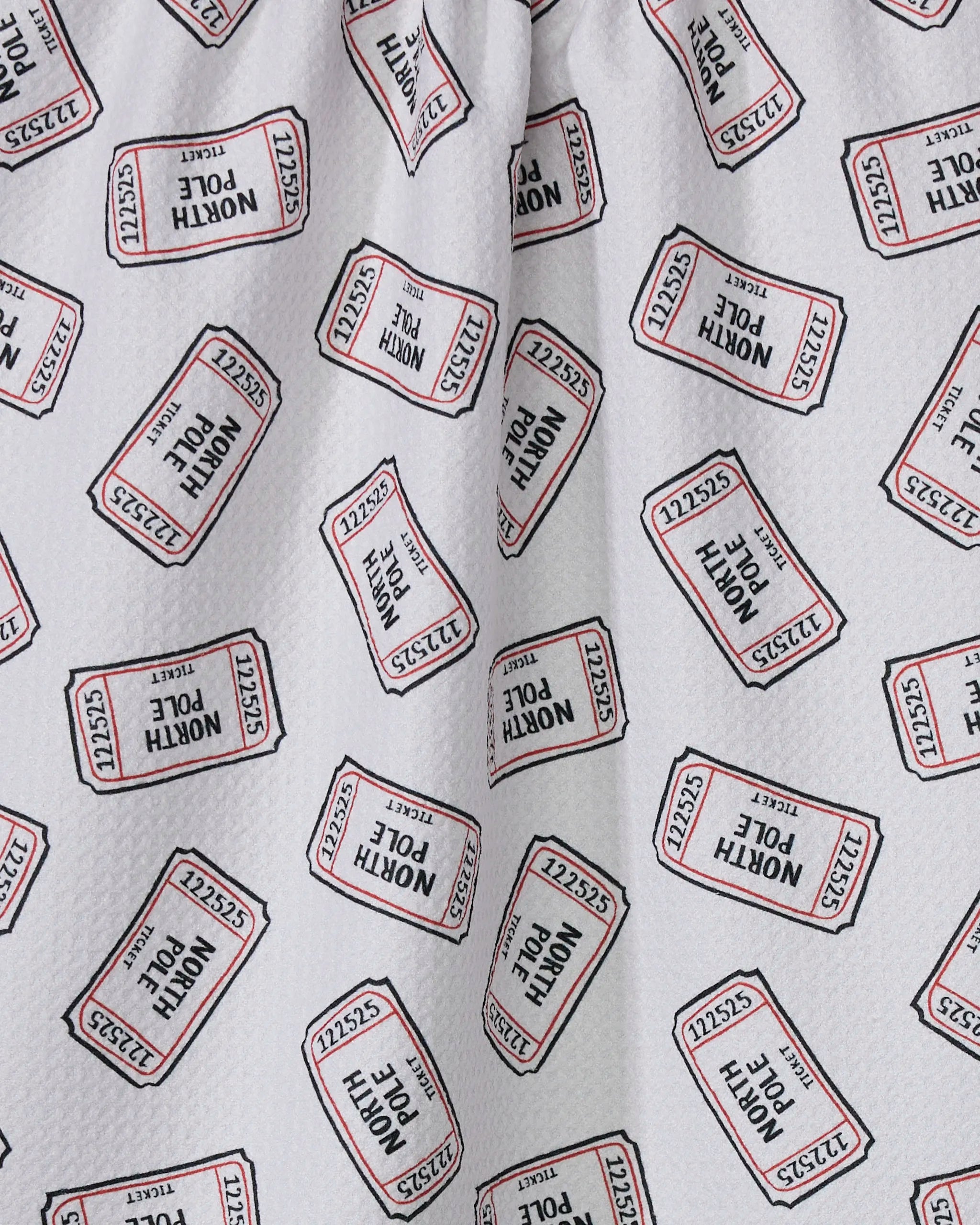 Close-up of a Geometry Golden Pass kitchen tea towel made from recycled materials, showcasing white fabric with red and black "ADMIT ONE" ticket designs and unique numbers in various orientations.