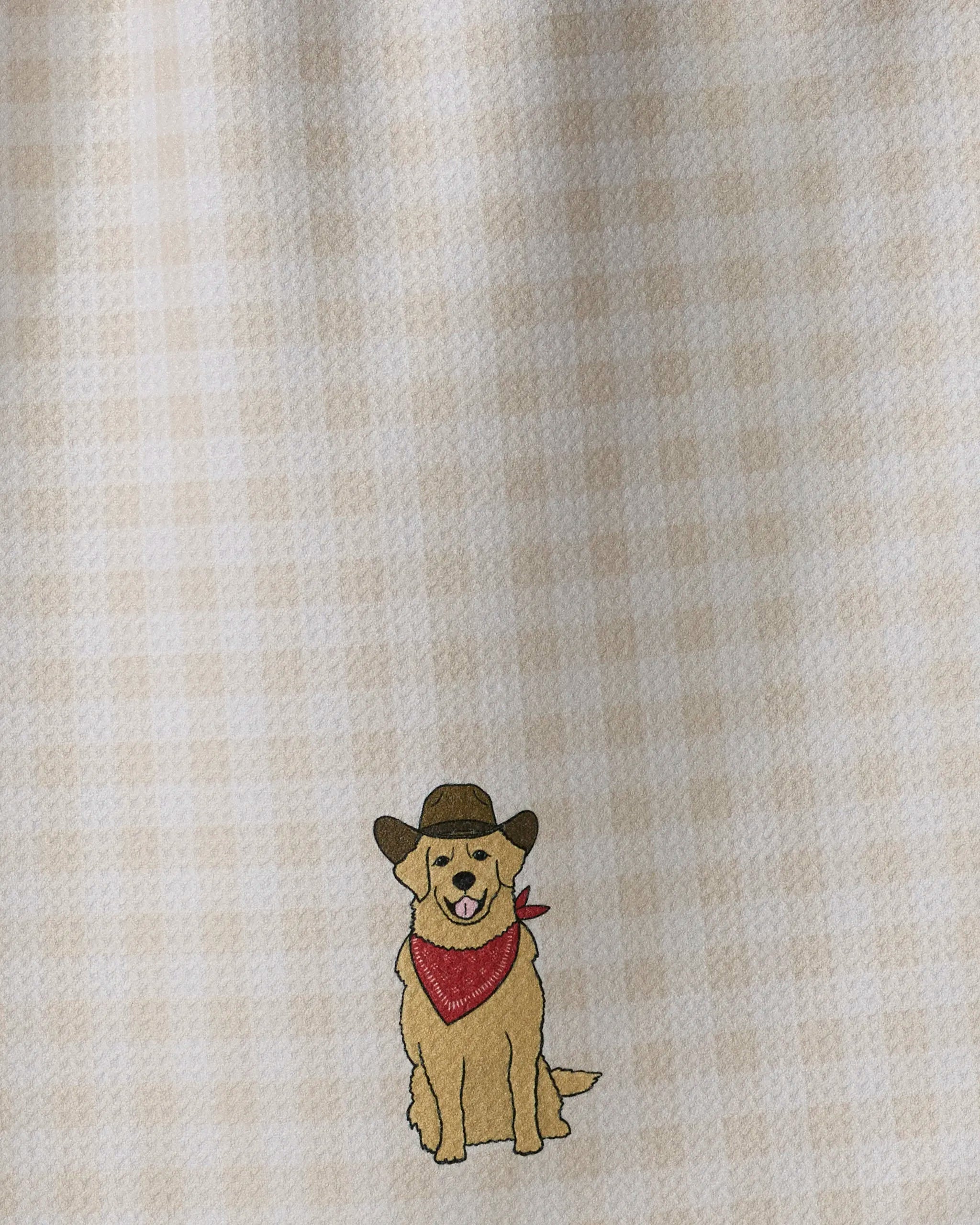 A charming embroidered dog donning a cowboy hat and red bandana sits against a beige plaid background, featured on Geometry’s ultra-absorbent recycled kitchen towel, the Golden Western.