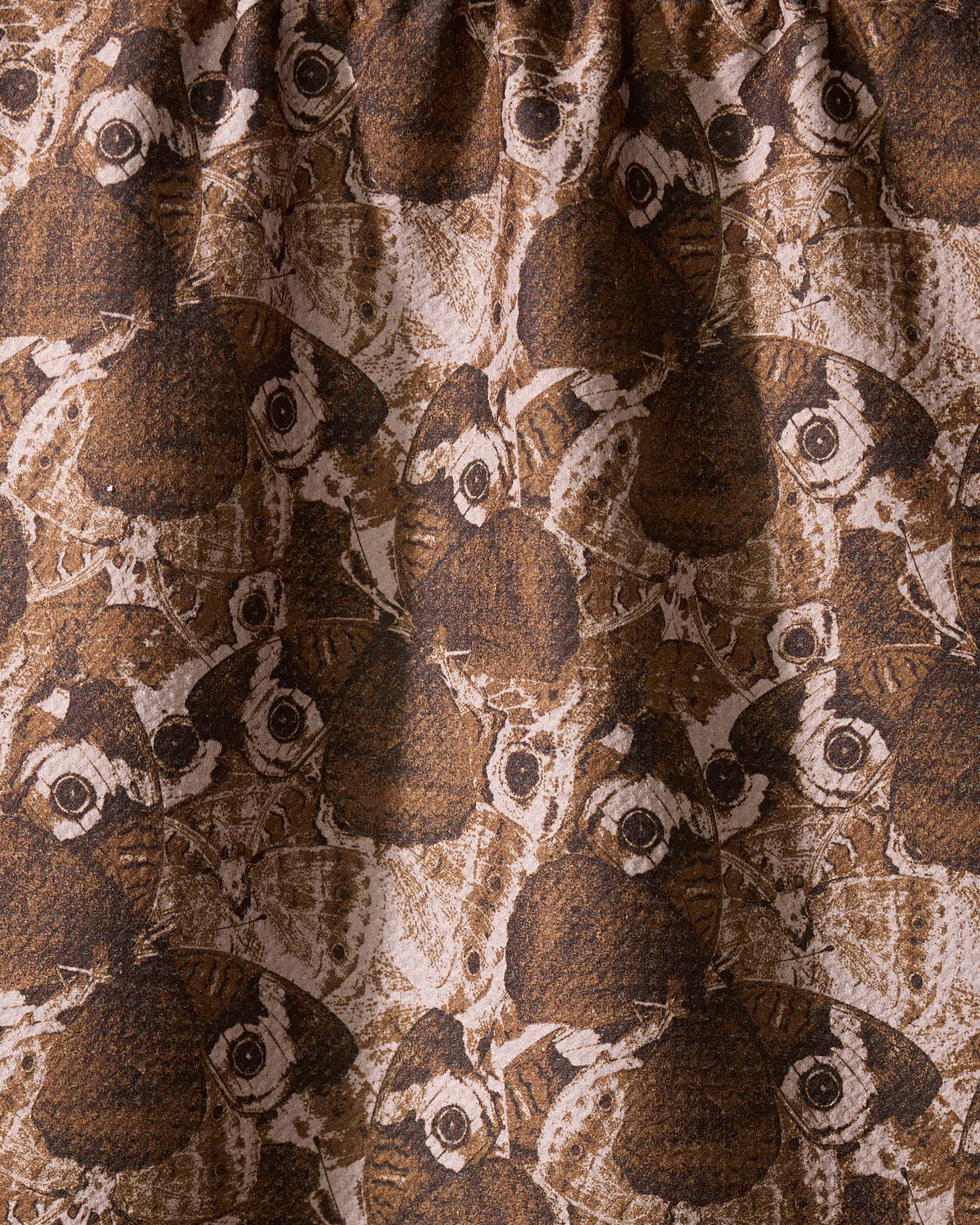 A close-up of Geometry’s Gossamer Flight tea towel showcases its Geoweave fabric, featuring overlapping brown and beige moths with detailed wings and eye spots for a textured, intricate design.