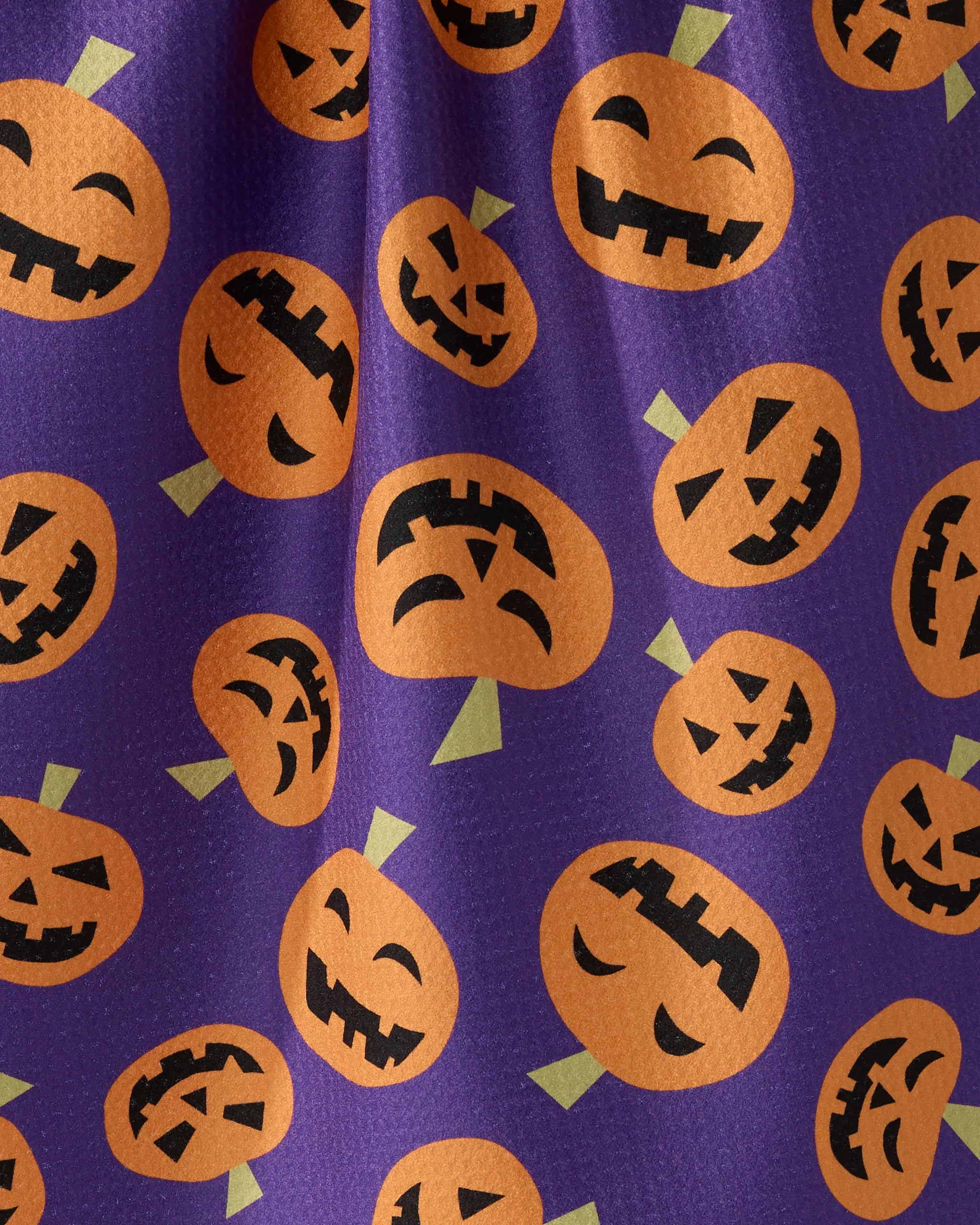 Geometry’s “Gourd Gang” is a purple tea towel featuring orange jack-o-lantern faces with green stems, each showing spooky and funny expressions. Made from recycled materials, this festive Halloween design is eco-friendly and fun.
