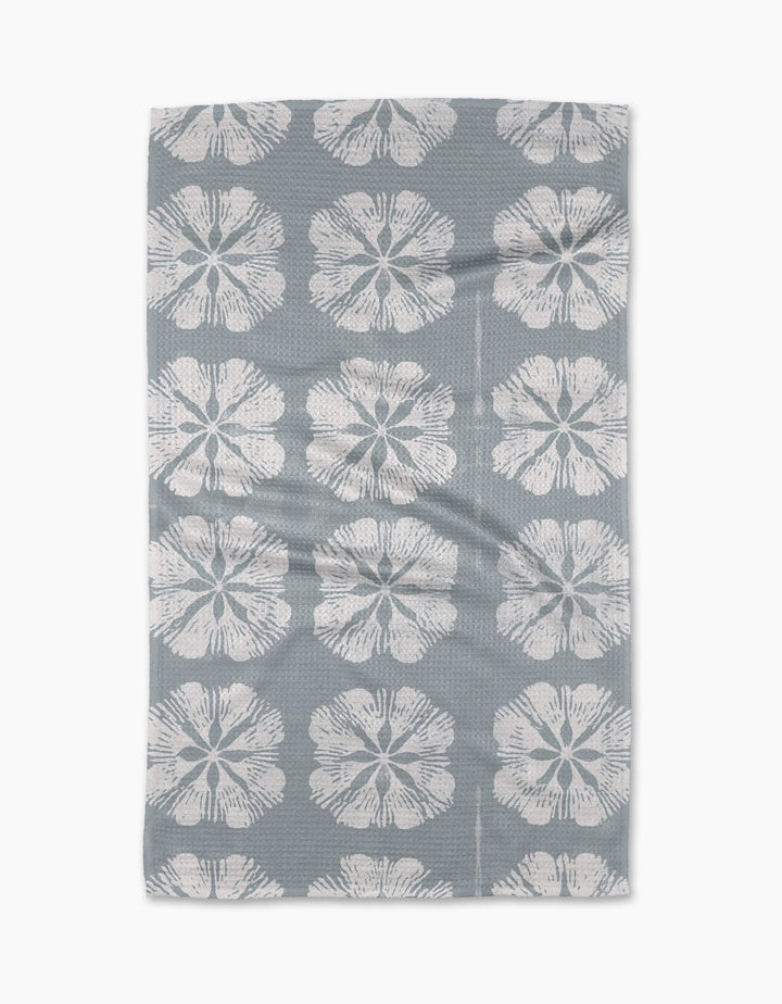 The Geometry Gracie Tea Towel is rectangular and grey, with large white stylized flowers in neat rows. Made from Geoweave fabric, the towel lies flat with slight folds visible.