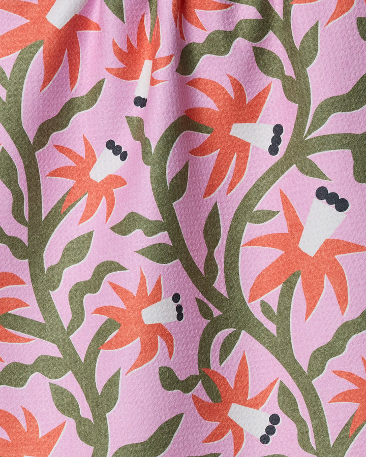 The "Graphic Flowers" tea towel by Claire Iglesias showcases red-orange flowers with green stems on a pink background, plus white accents and black-dotted centers. Its ultra-absorbent, dimpled texture makes it both stylish and functional for the kitchen.