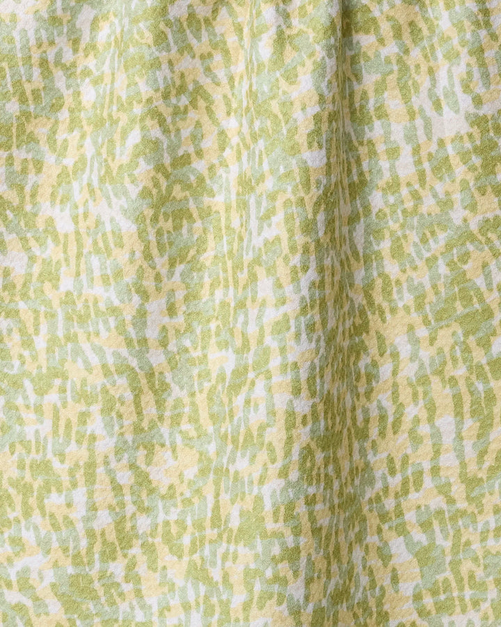 A close-up of the Geometry Grassy Field tea towel, featuring an absorbent fabric with a light green, yellow, and white abstract brushstroke pattern and a slightly gathered texture.