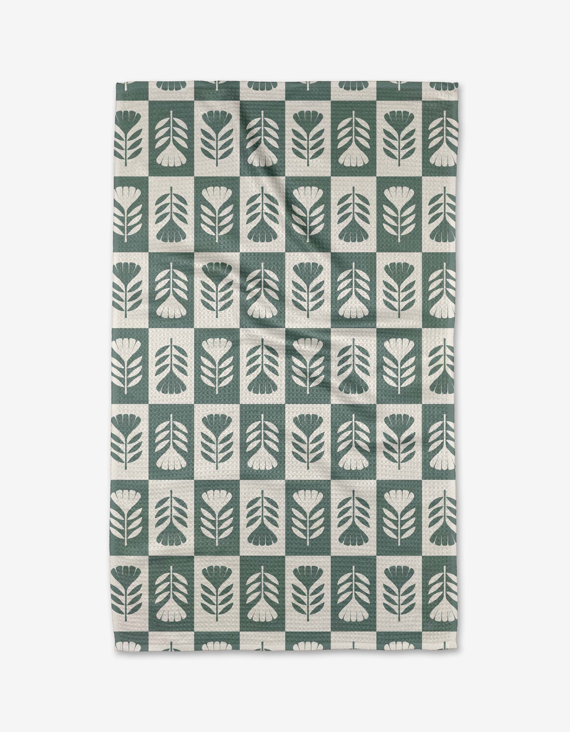 The Green Flower Patch tea towel by Charlie Rowan Designs features a grid of stylized green and white flowers and leaves. Crafted from Geoweave fabric, it blends modern style with superior absorbency.