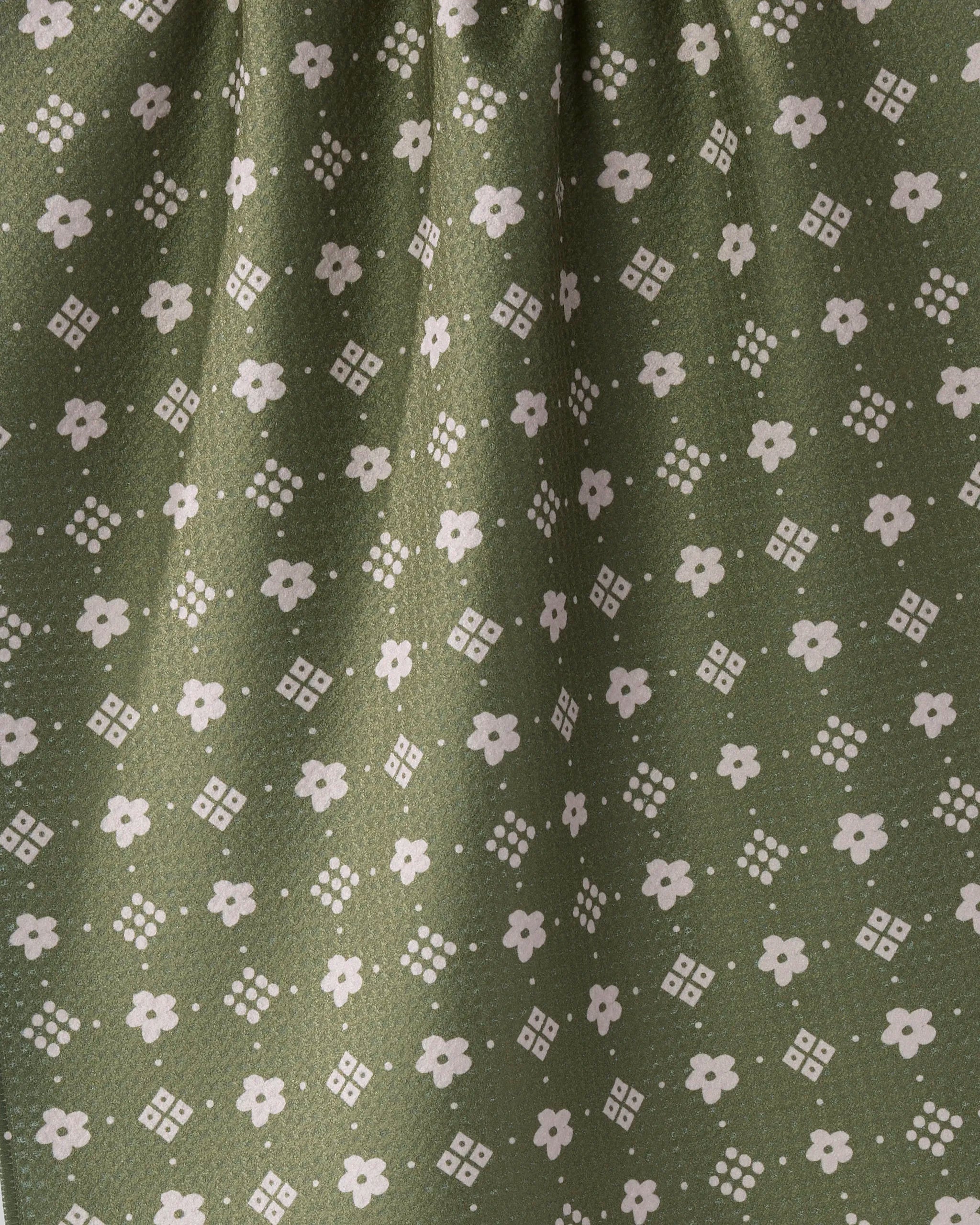 The Geometry Green Gables tea towel is made from recycled materials and showcases a pattern of small white flowers with diamond shapes on an olive background, plus gentle gathers at the top for texture.