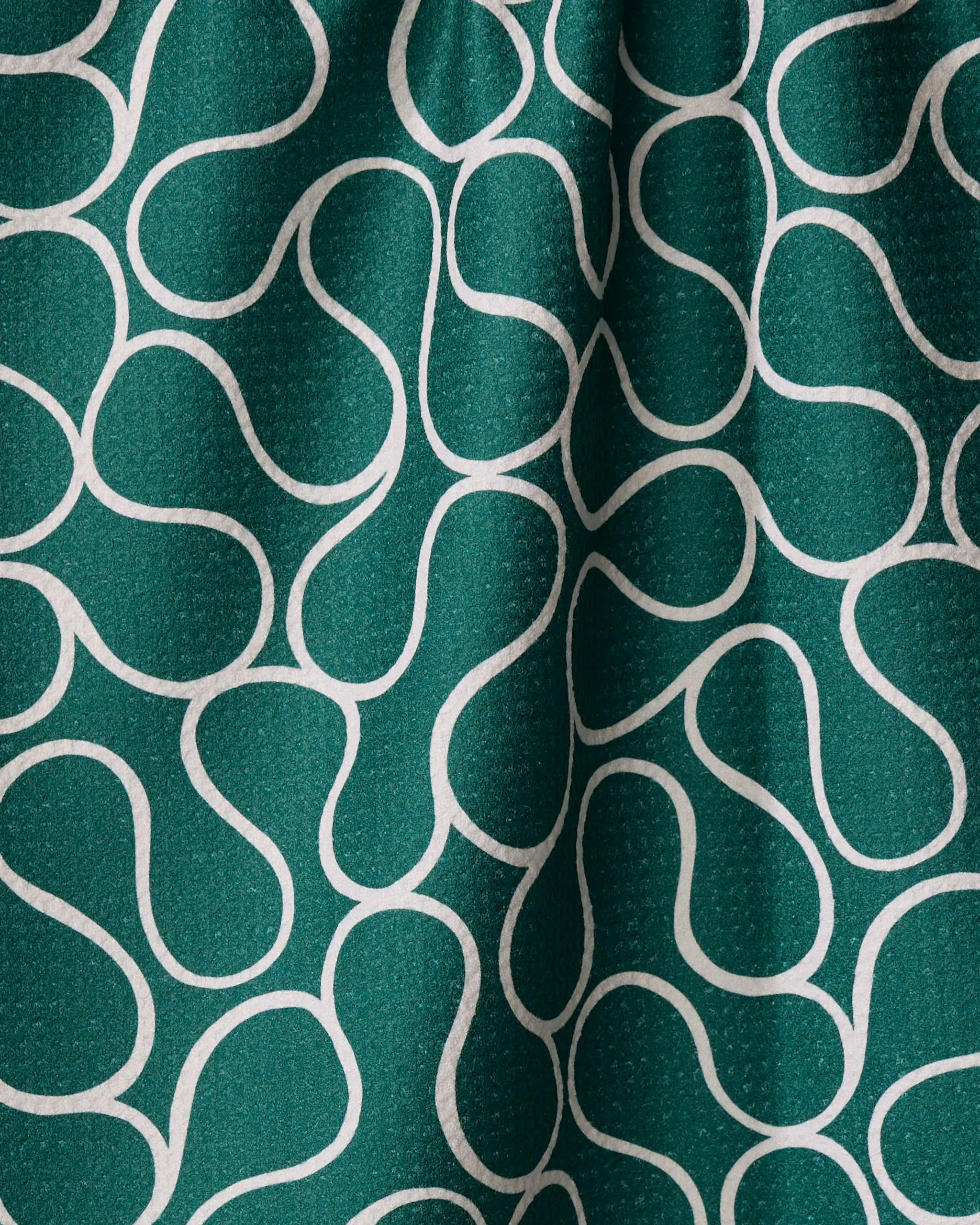 The Gerdadzy "Green Loops" towel features a wavy white abstract design on green fabric, with ultra-absorbent material and gentle folds that create subtle shadows and highlights.