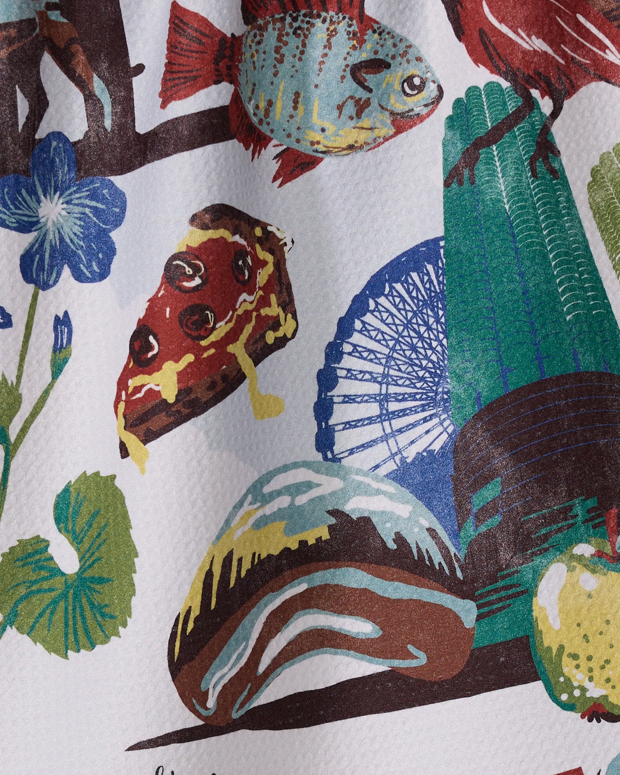 The "Greetings From Illinois" tea towel by Geometry features a vibrant design of pizza, fish, a Ferris wheel, plants, a flower, and a large pastry on textured fabric made from recycled materials.
