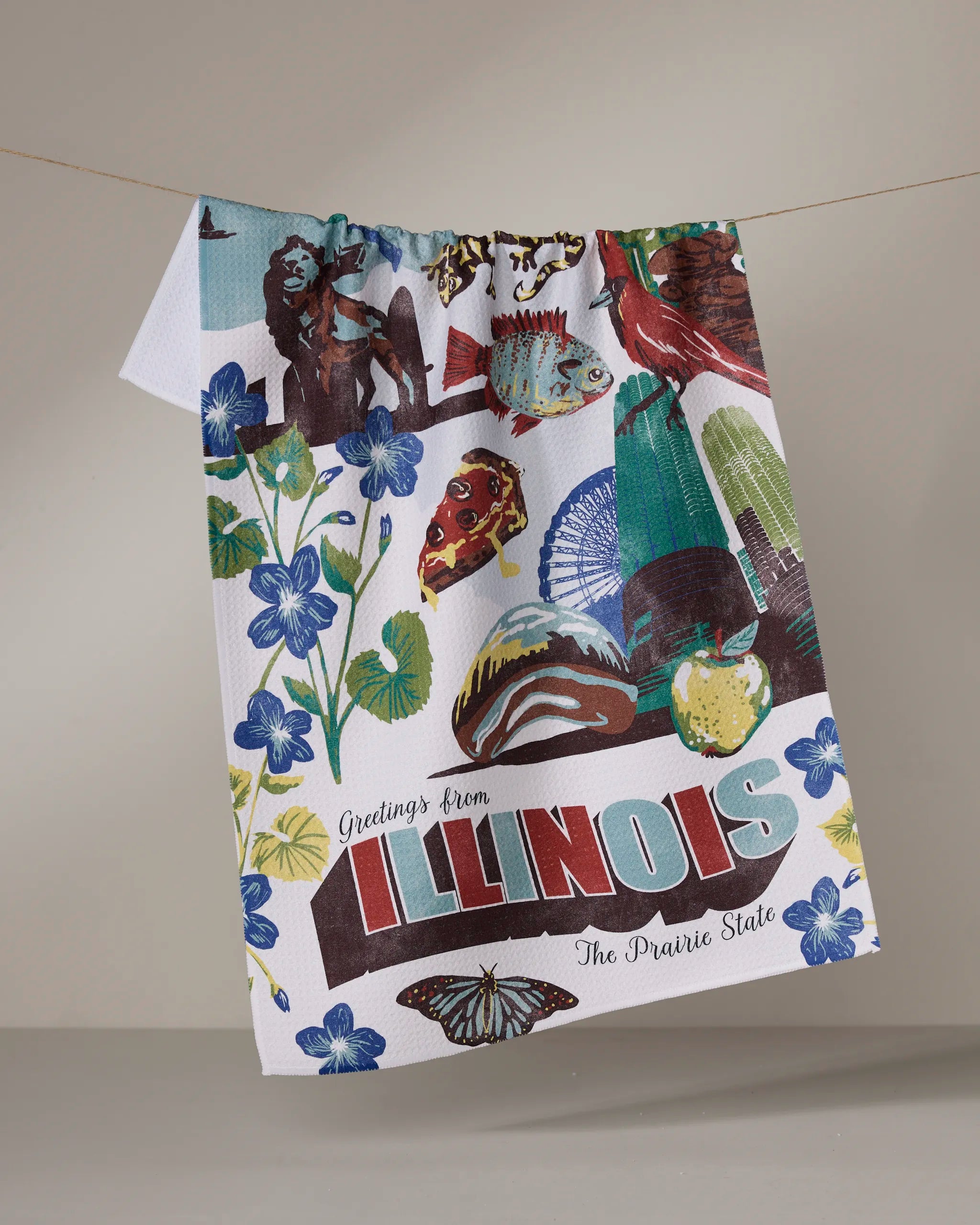 The Geometry "Greetings From Illinois" kitchen towel features vibrant illustrations of state flowers, animals, fish, and landmarks, all beautifully crafted from recycled materials.