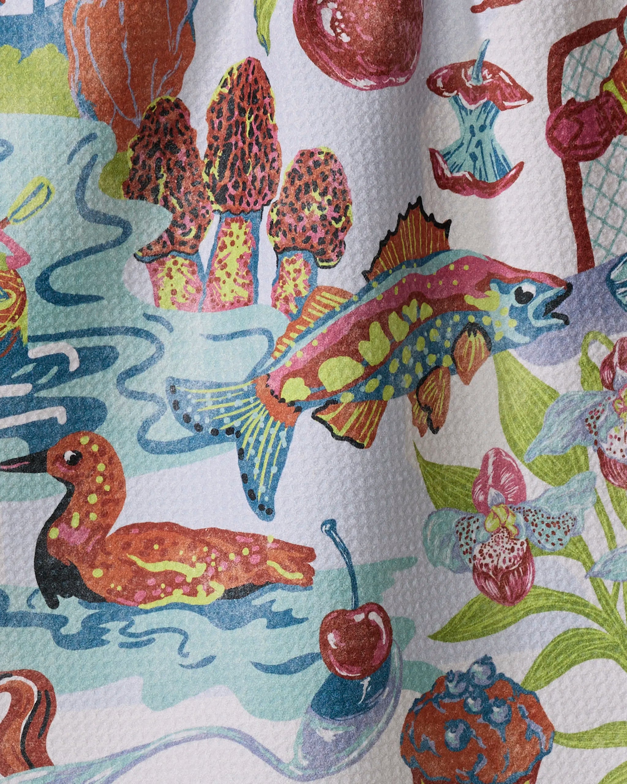 The Geometry "Greetings From Minnesota" tea towel showcases a vibrant fish with blue, yellow, and orange markings alongside mushrooms, a red bird, cherry, orchids, blue streams, and plants on textured recycled material.
