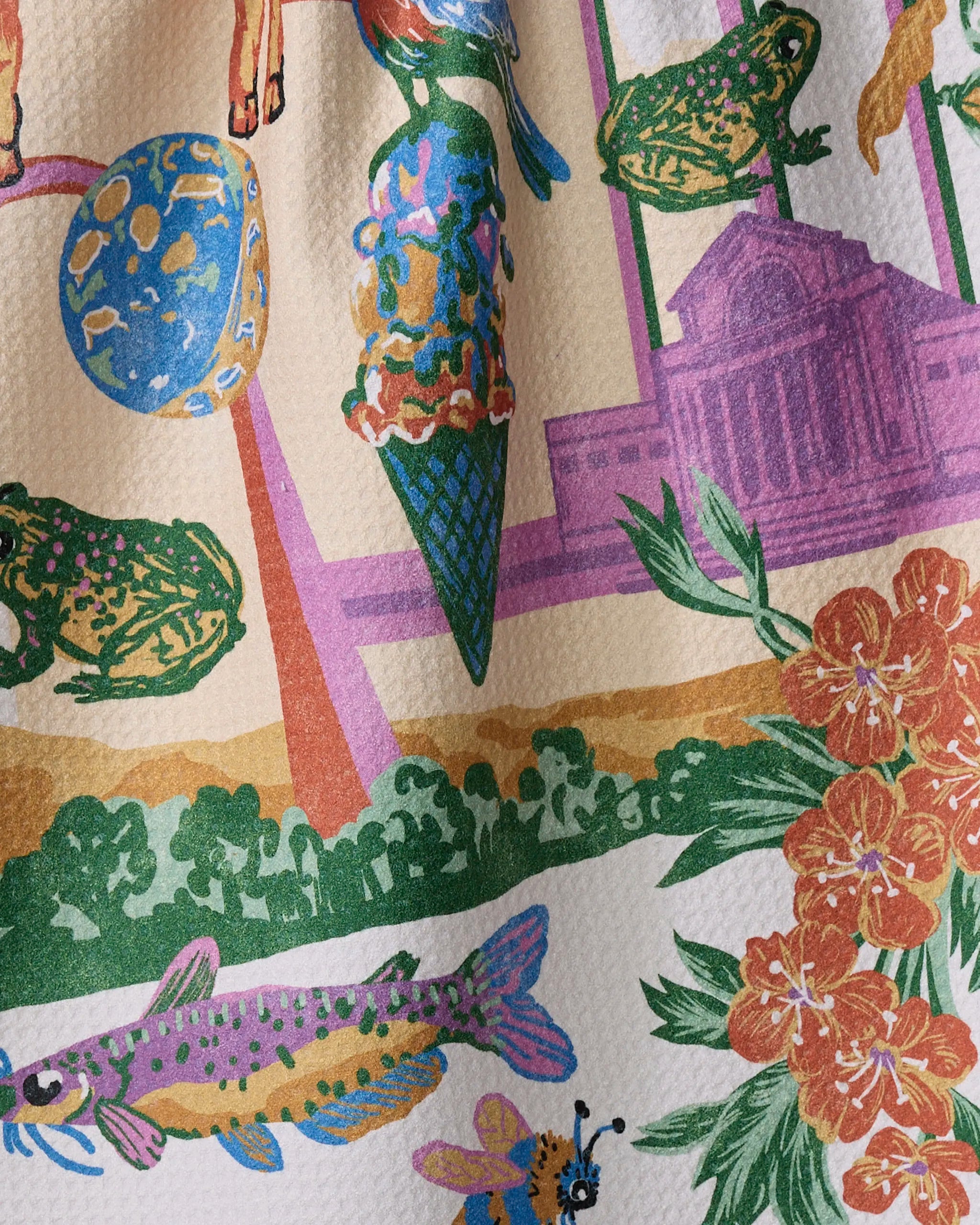 The Geometry "Greetings From Missouri" tea towel showcases frogs, a purple fish, an ice cream cone, flowers, an abstract building, and a blue-yellow planet on soft Geoweave fabric for a vibrant look and feel.