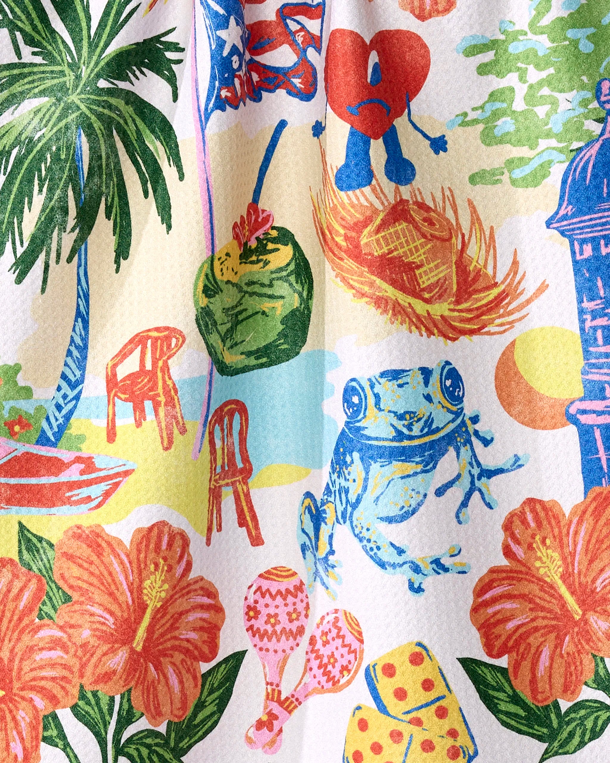 The Geometry "Greetings From Puerto Rico" ultra-absorbent tea towel features a colorful illustration of palm trees, red chairs, a coconut drink, sad heart cartoon, blue frog, lighthouse, tropical flowers, hot air balloons, and a sunset—crafted from recycled materials.