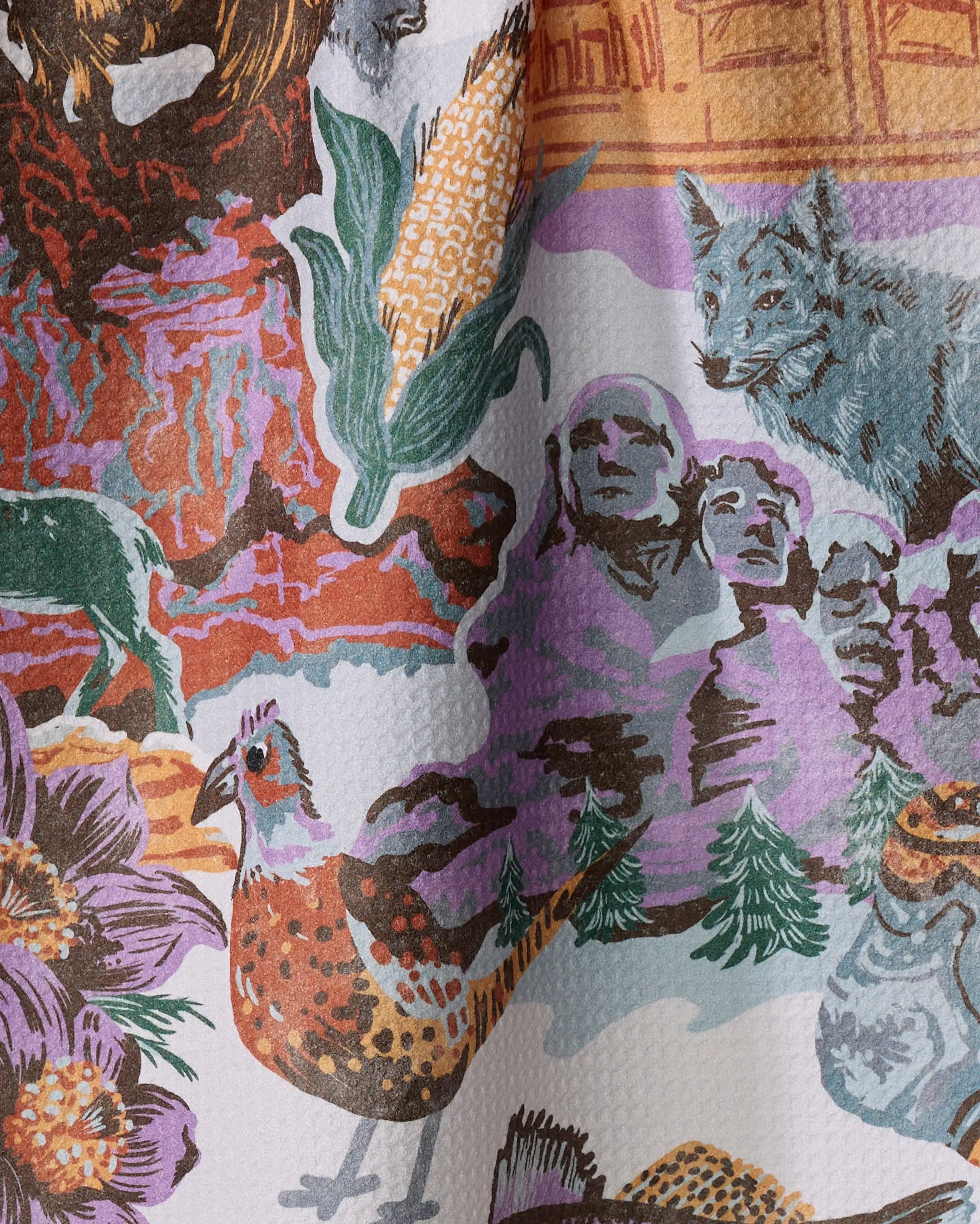 The Geometry "Greetings From South Dakota" tea towel features a vibrant illustration of Mount Rushmore, a corn cob, wildlife, and flowers—all printed on eco-friendly recycled material.