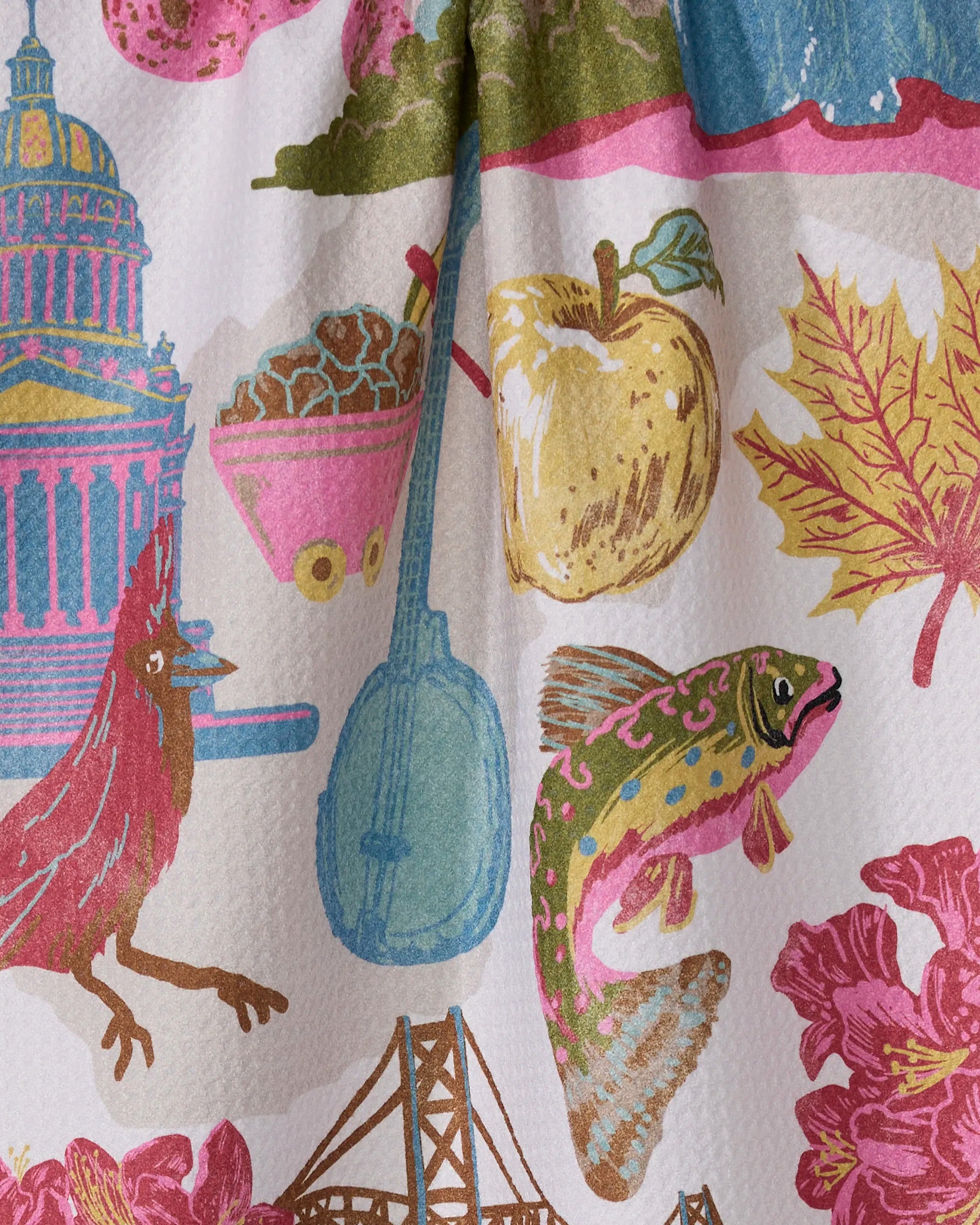 The "Greetings From West Virginia" tea towel by Geometry features a vibrant design with a banjo, fish, apple, cardinal, bridge, Capitol dome, leaf, and flowers on textured fabric—perfect for your kitchen and made from recycled materials.