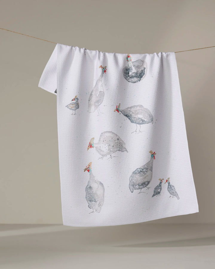 The "Guinea Fowls" tea towel by Taryn Brennan features watercolor guinea fowl illustrations on a plain light background. Made from quick-drying recycled materials, it hangs perfectly for display or everyday use.