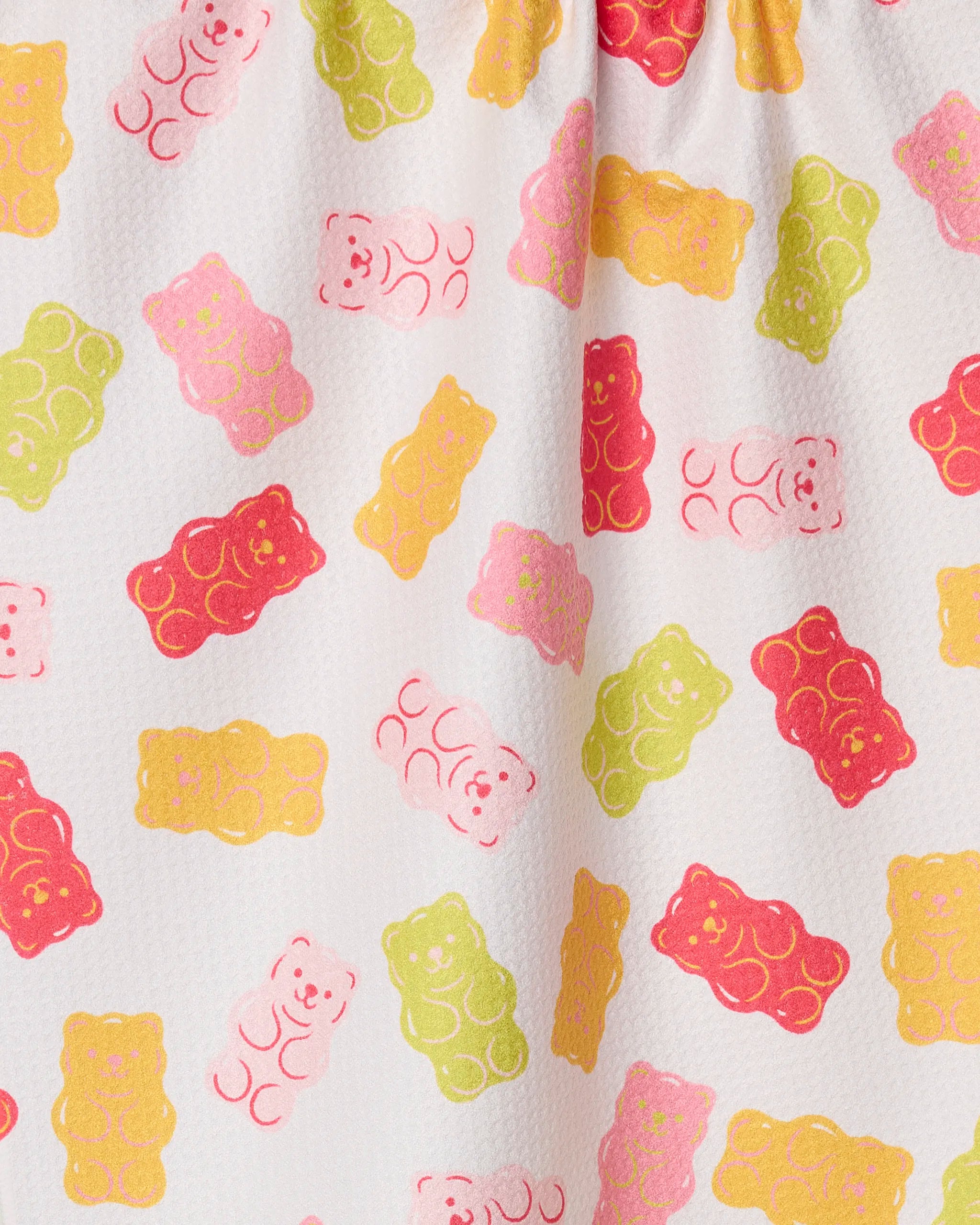 The Gummy Bear tea towel by Vaishali Design Studio features playful red, pink, yellow, and green gummy bear illustrations on a white textured background and is made from ultra-absorbent recycled materials.