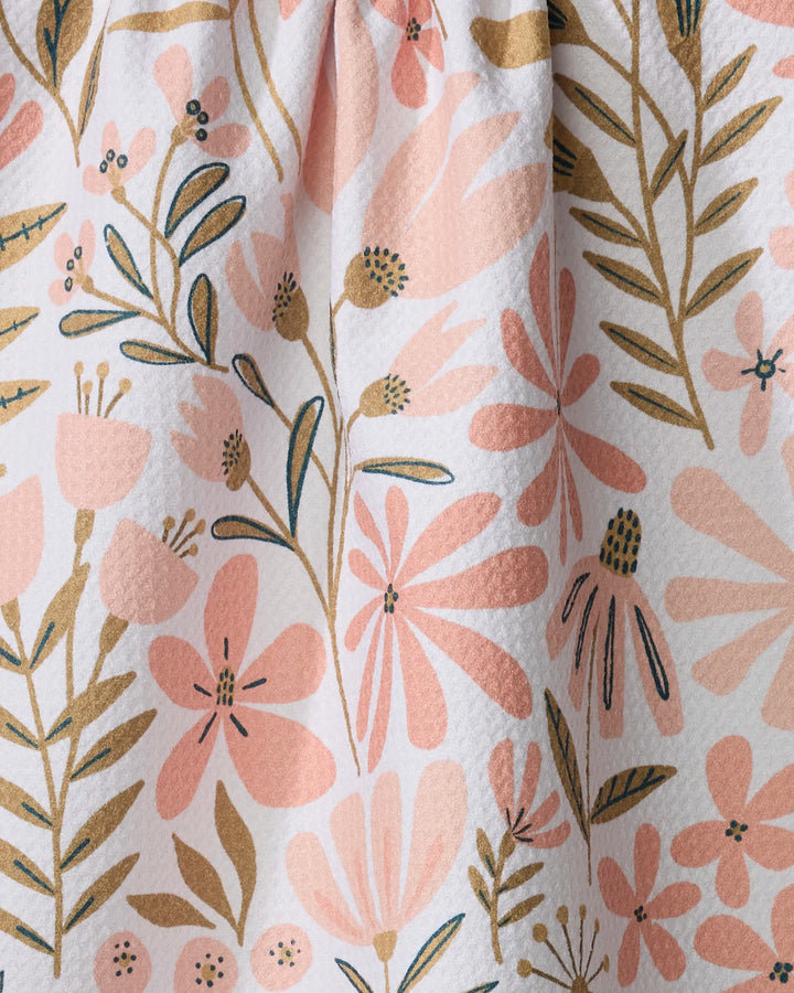 Close-up of Halia, a recycled kitchen towel by Amy MacCready, showcasing textured fabric adorned with pink and beige flowers and green leaves on a light background.