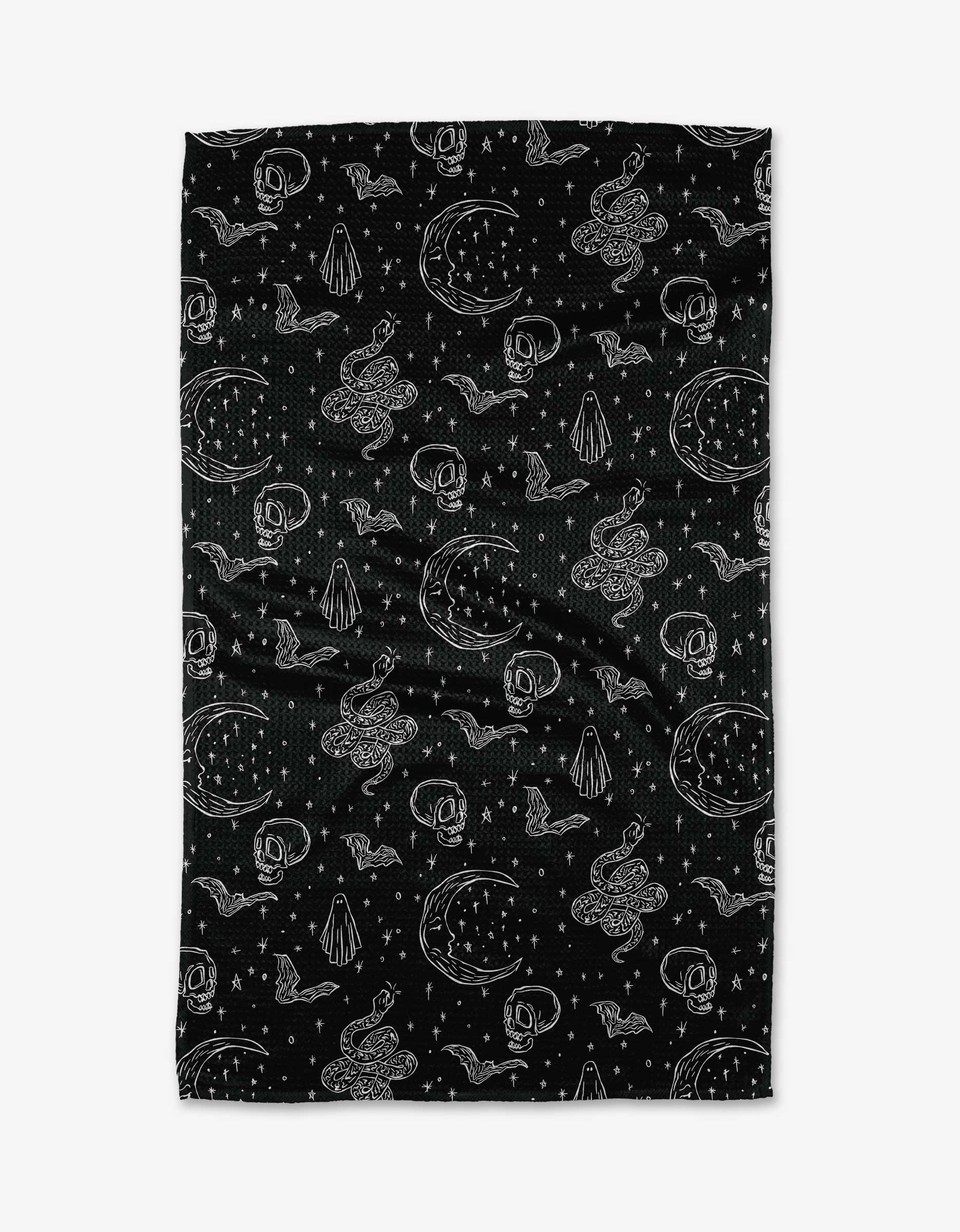 The Halloween Hauntings kitchen towel by Aubrey Fairchild features a white, hand-drawn pattern of crescent moons, snakes, crystals, stars, clouds, and skulls scattered on a black recycled fabric.