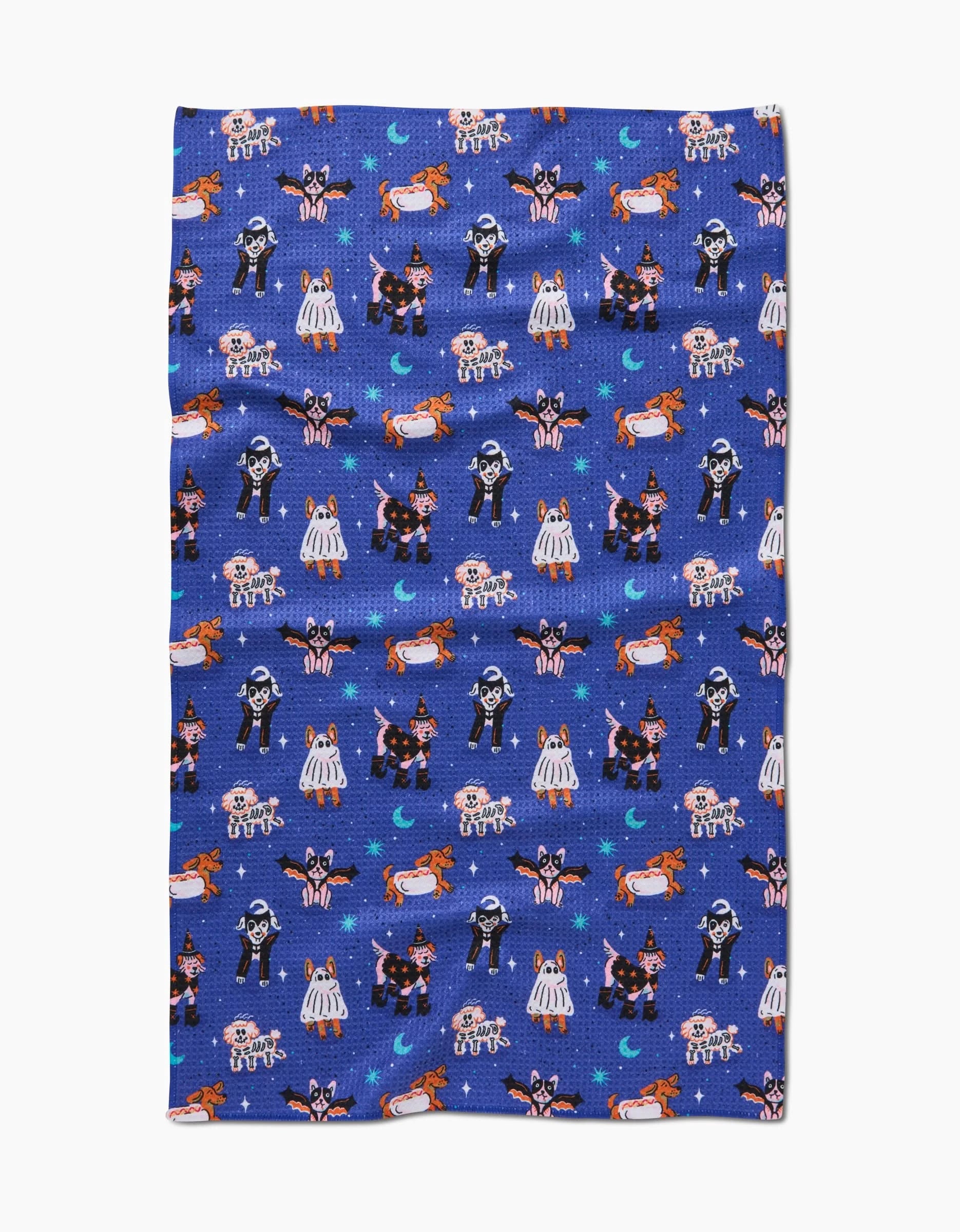 The Halloween Hounds tea towel by Camila Leão features blue Geoweave fabric with cartoon Halloween characters, crescent moons, and stars in a repeating pattern.