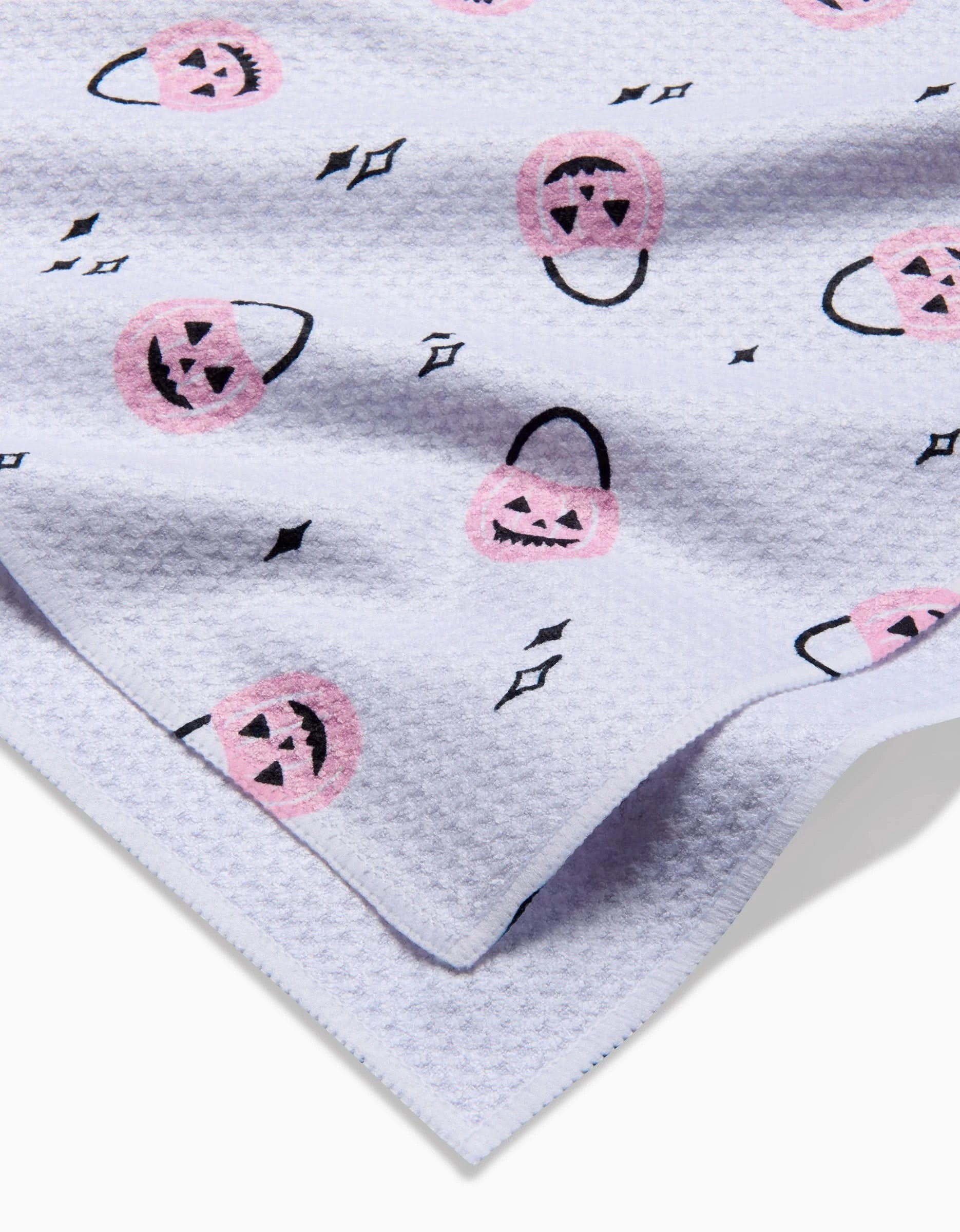 The Hufton Studio Halloween Pumpkin Bucket tea towel features a white textured fabric with pink jack-o-lantern candy buckets and black diamonds scattered across its ultra-absorbent surface.