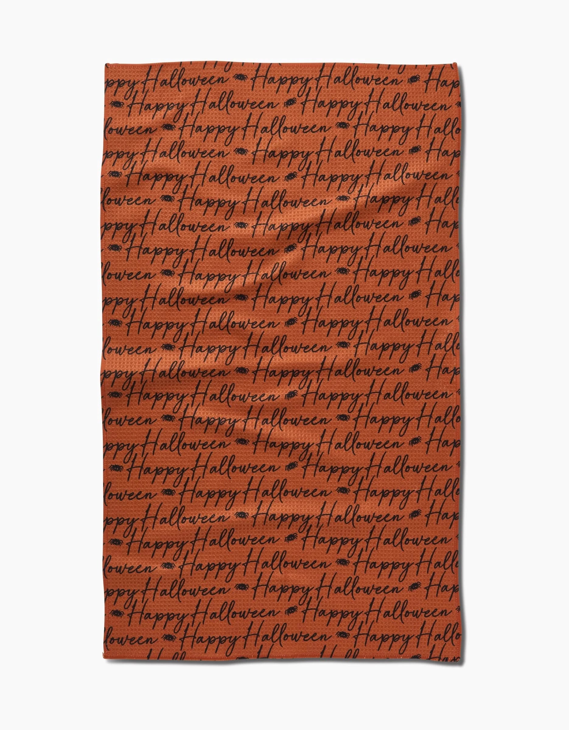 The Geometry Halloween Script Orange tea towel features rows of black cursive happy halloween on bright orange fabric, perfect for adding festive flair to your kitchen.