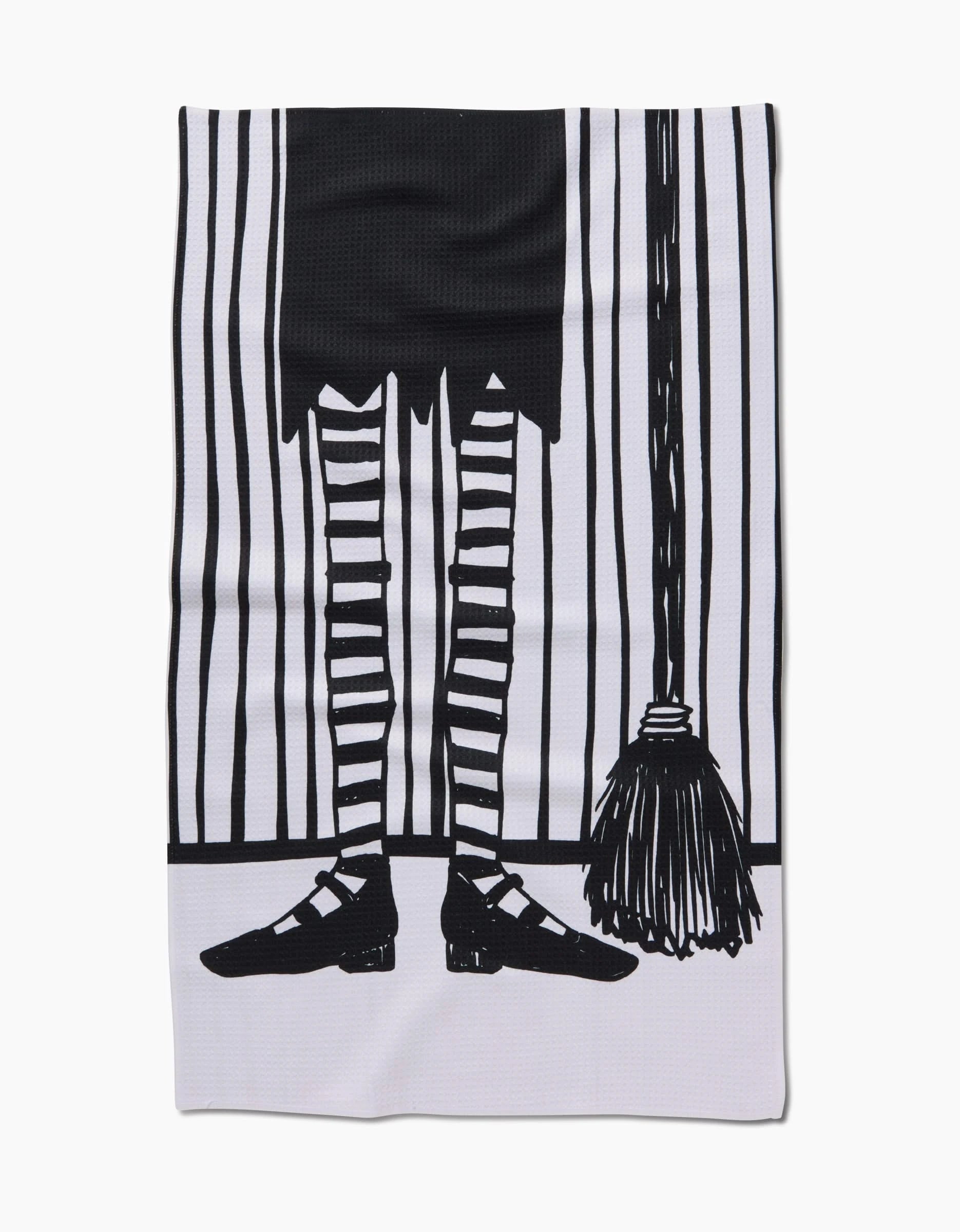 A black and white illustration of a person in a skirt with striped stockings and black shoes stands by a broom on a striped background—an ideal design for the Halloween Witch Legs tea towel by Hufton Studio, made from recycled materials.