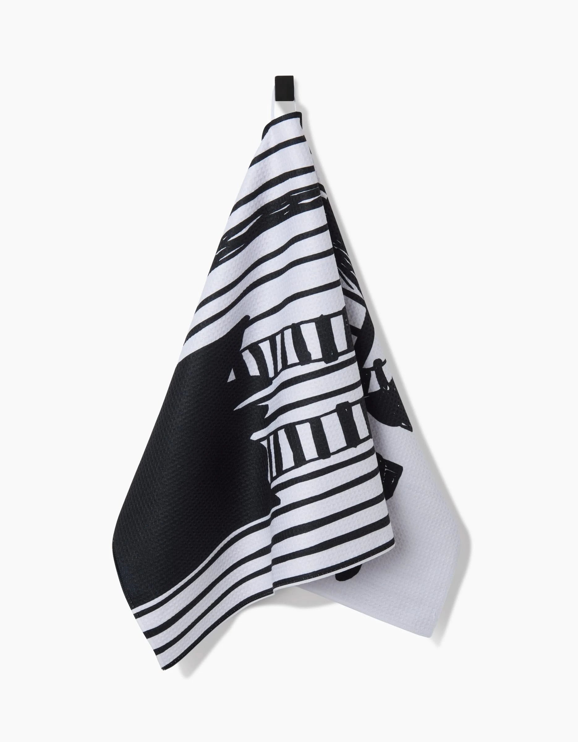The Halloween Witch Legs by Hufton Studio hang from a black loop against a white background, featuring black horizontal stripes and an abstract design, crafted from recycled materials.