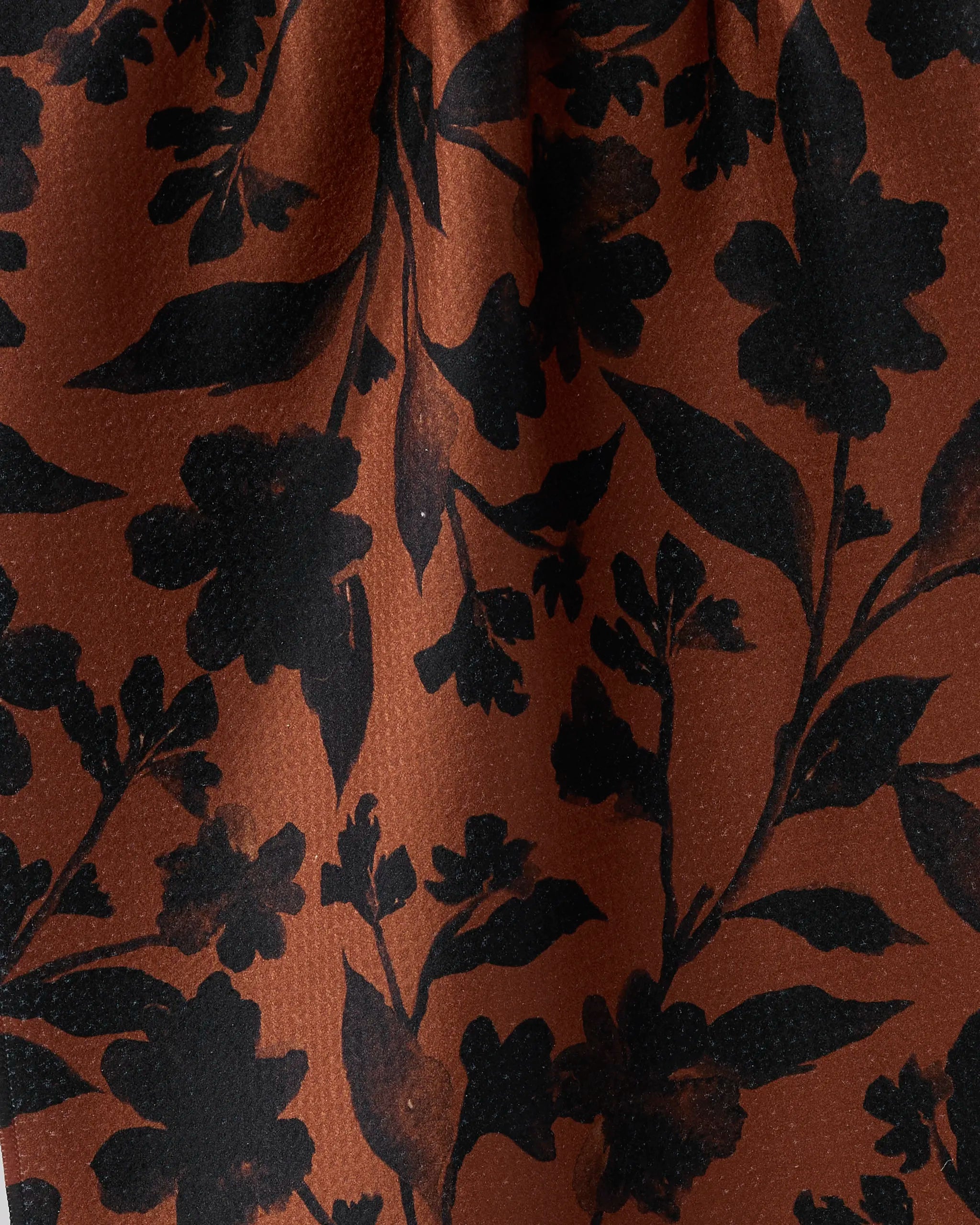 Close-up of the Hallowell dish towel by Geometry, featuring a brown background with black floral patterns—various leaves and flower shapes—crafted for absorbency and perfect for everyday kitchen use.