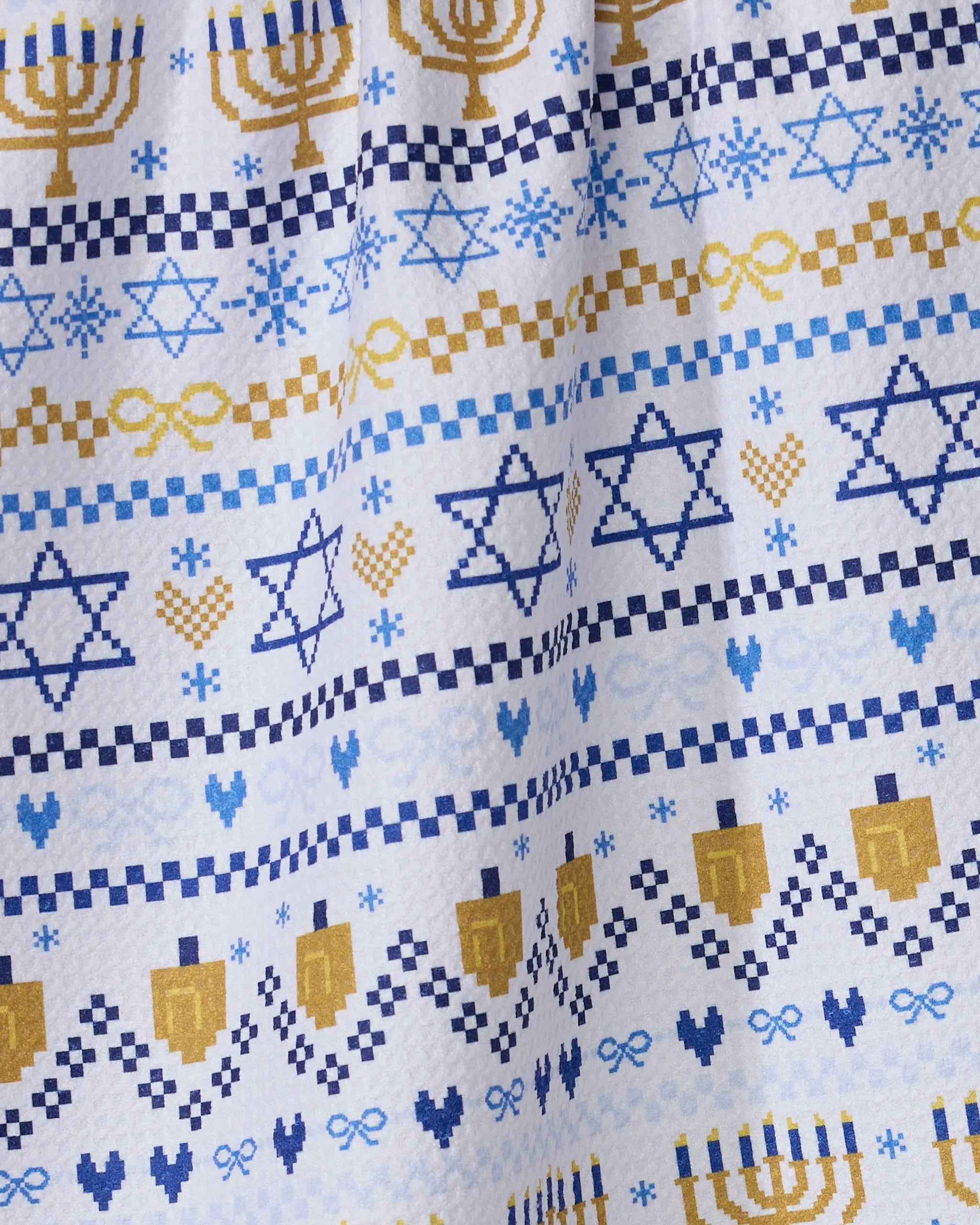 The Geometry Hanukkah Sweater kitchen towel features festive, eco-friendly designs with blue Stars of David, gold menorahs, dreidels, hearts, and geometric patterns on a crisp white background.