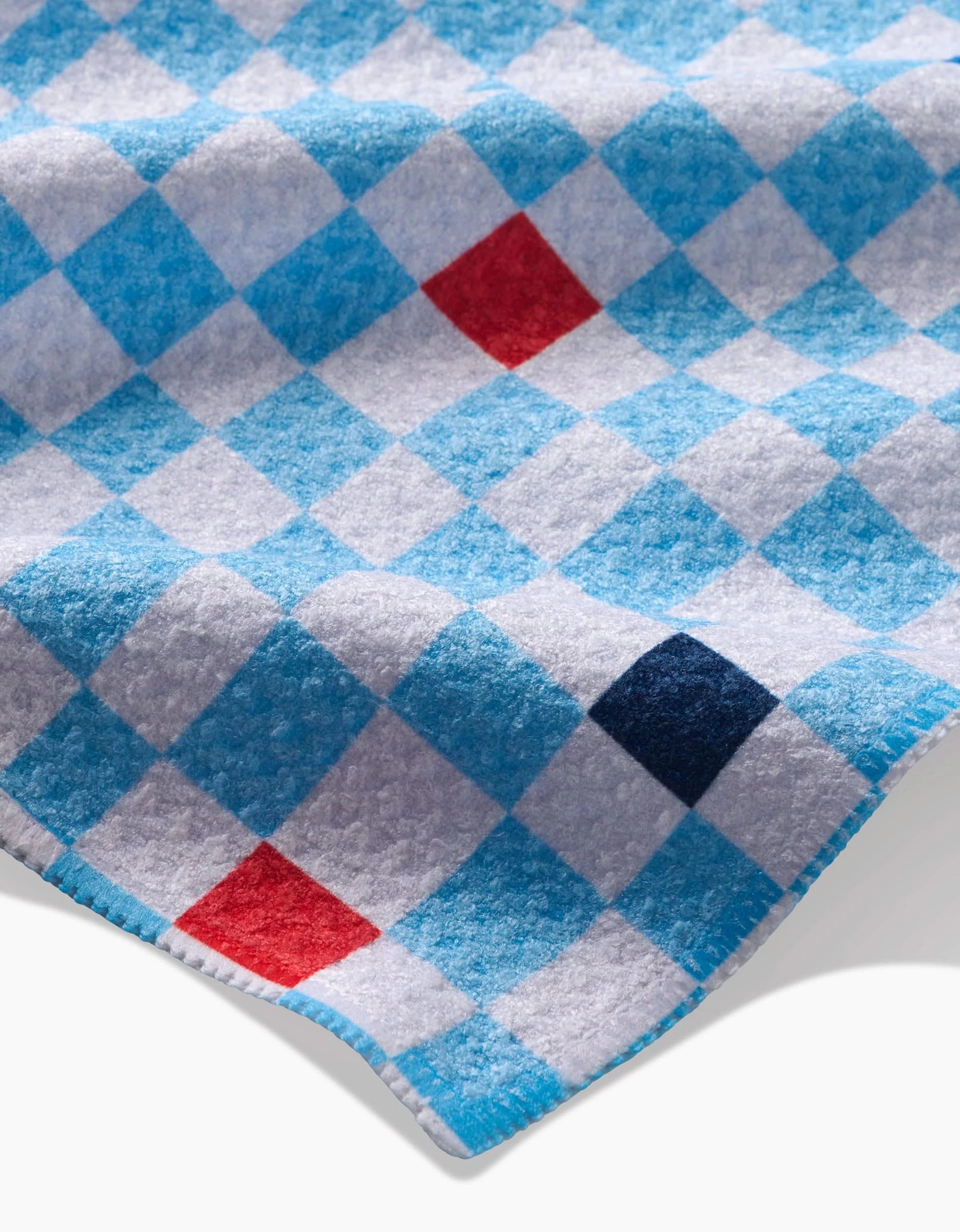 The Happy Hemera Happy Check features soft Geoweave™ fabric with a blue and white checkered pattern, accented by red and navy squares. Shown close up, the fabric has a slightly wavy surface and neatly finished edges.