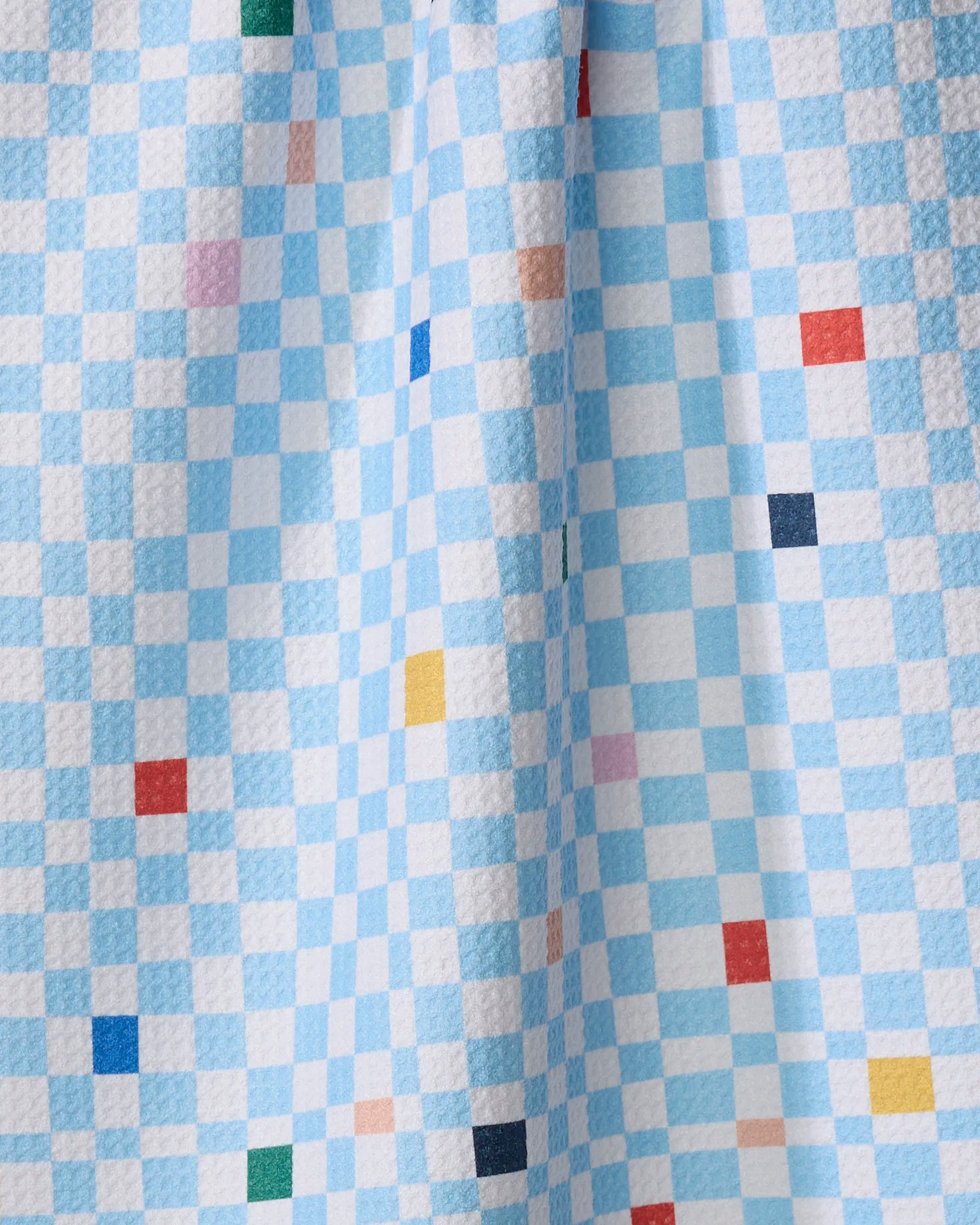 The Happy Hemera "Happy Check" tea towel features a textured blue and white checkered fabric with colorful squares in red, yellow, green, pink, and navy. Quick-drying and soft-draping, it's perfect for brightening your kitchen.