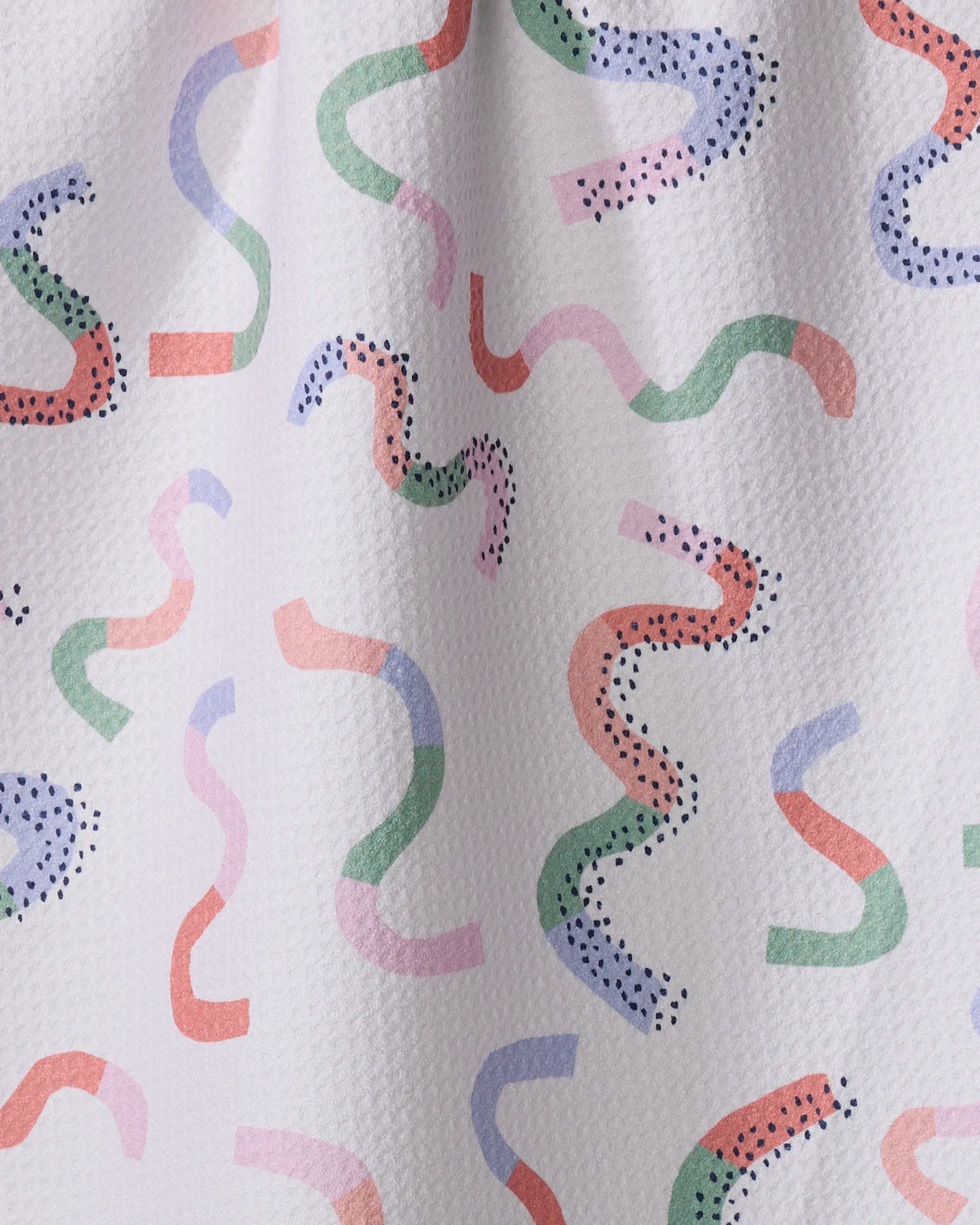 The Claire Iglesias "Happy Streamers" kitchen towel is white and textured, with pastel green, pink, blue, and purple squiggly lines and dotted accents for a playful abstract look.