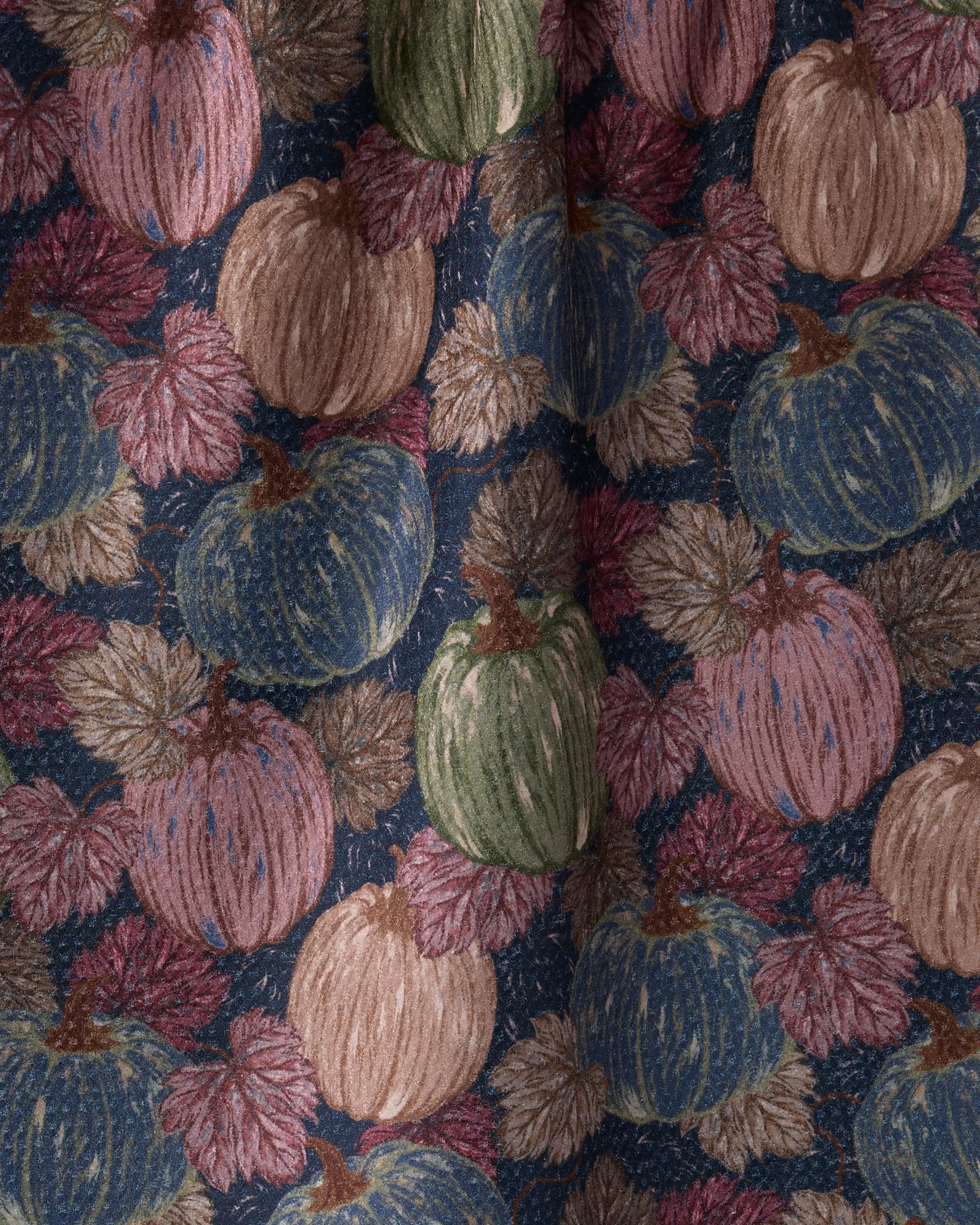 The Geometry Harvest Moon kitchen towel features pumpkins in green, blue, and tan with brown and maroon autumn leaves on a dark background. Its eco-friendly, softly woven texture is perfect for seasonal décor.