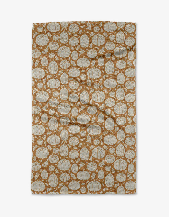 The Danelys Sidron Harvest Pumpkin Patch tea towel is made from eco-friendly Geoweave fabric and displays white pumpkin outlines on a brown background. The slightly wrinkled towel is shown laid flat on a white surface.