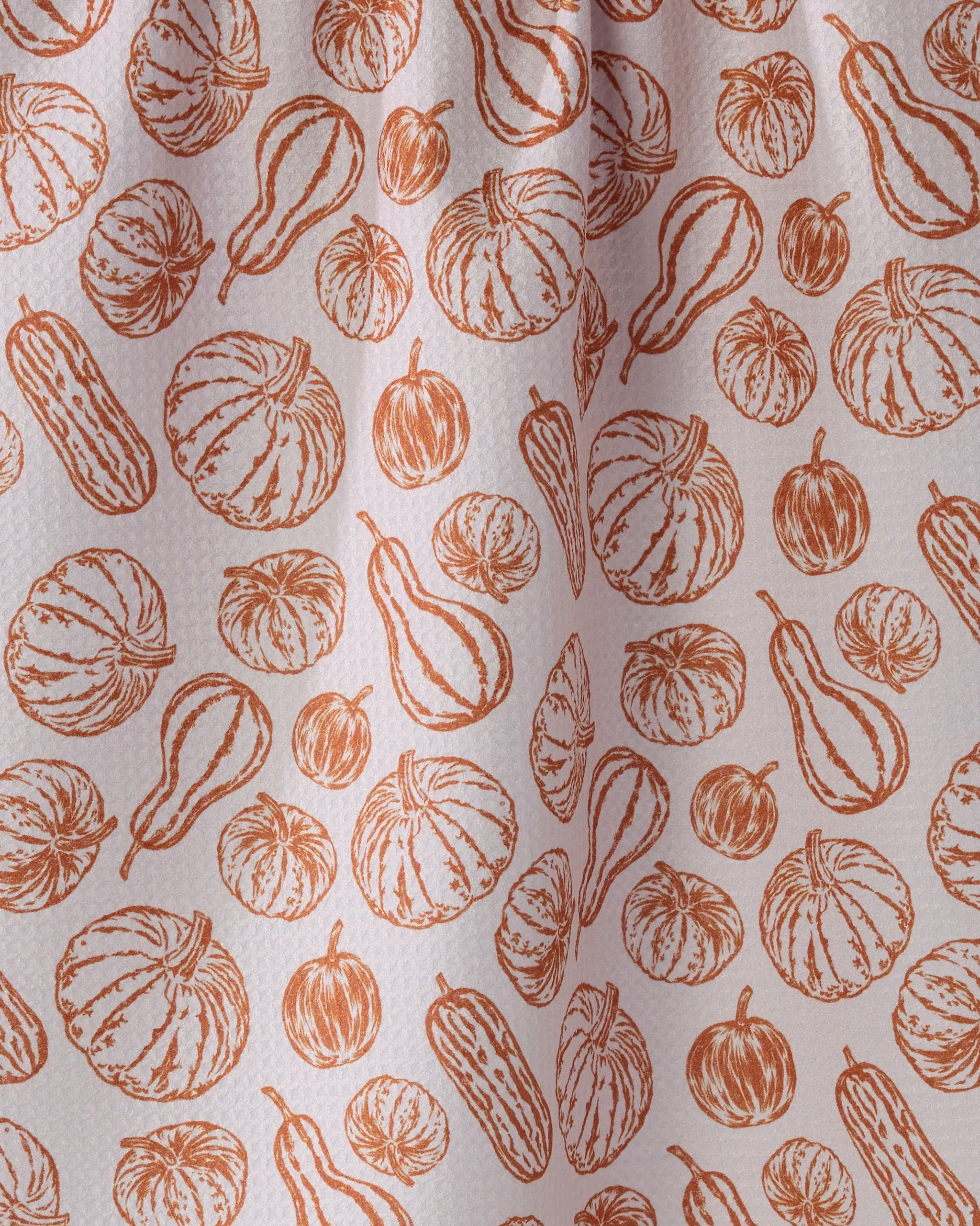 Close-up of Geometry's Harvest Sketch tea towel, featuring an orange pumpkin and gourd line art pattern on a light, textured background. Ultra-absorbent and eco-friendly fabric is gently draped.