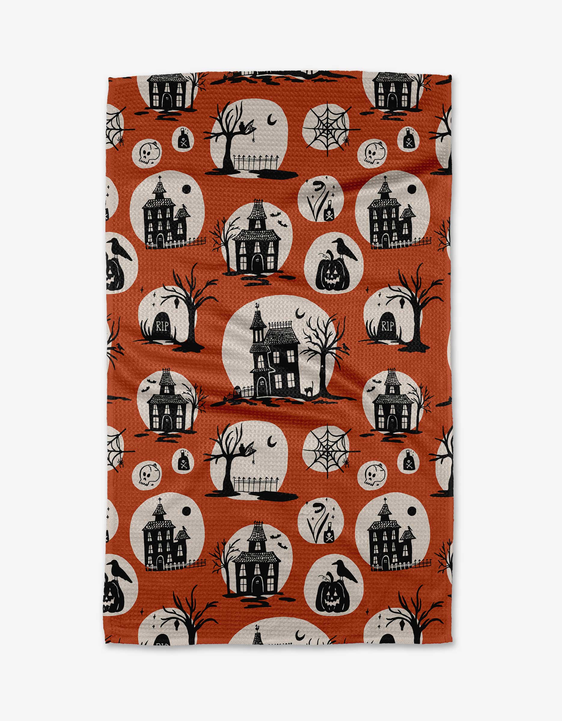 The Kayla Ann Haunted House orange tea towel features haunted houses, jack-o’-lanterns, and more spooky icons—a festive, eco-friendly kitchen accent made from recycled materials.