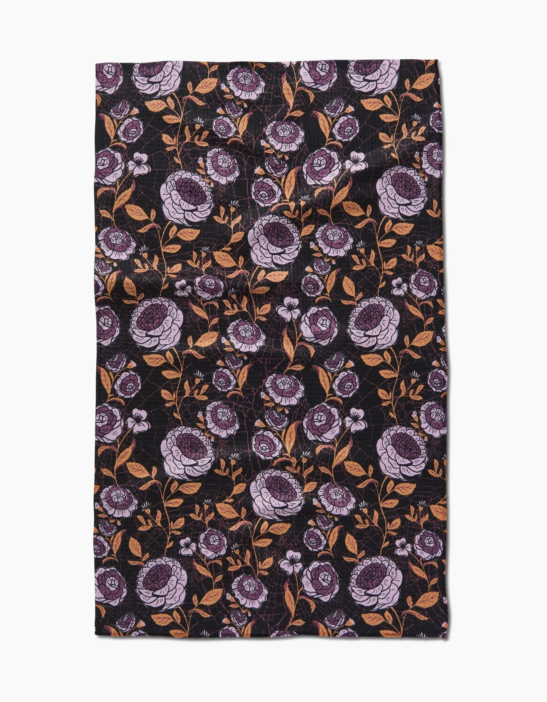 The Haunted Roses tea towel by Danelys Sidron features purple and lavender flowers with orange stems on a black background, crafted from recycled materials.