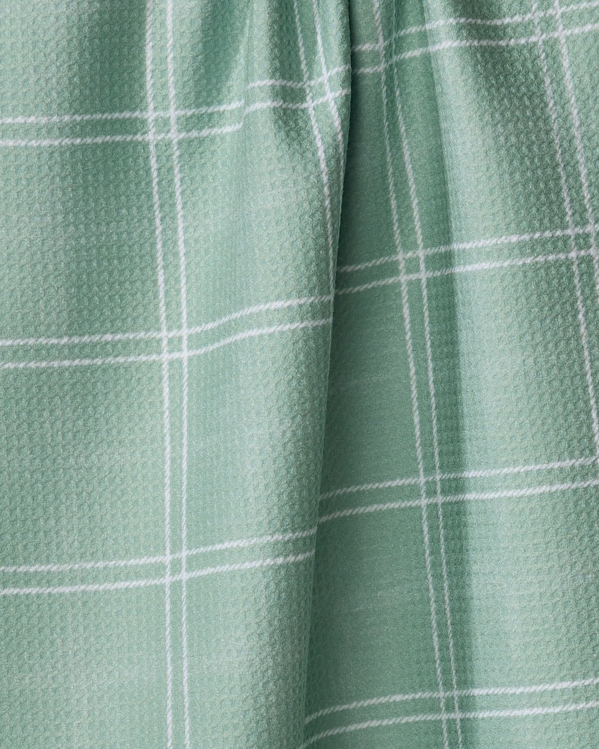 The Geometry Hearth Meadow dish towel features a light green absorbent fabric with a subtle textured pattern and thin white grid lines, displayed with a slightly gathered drape.