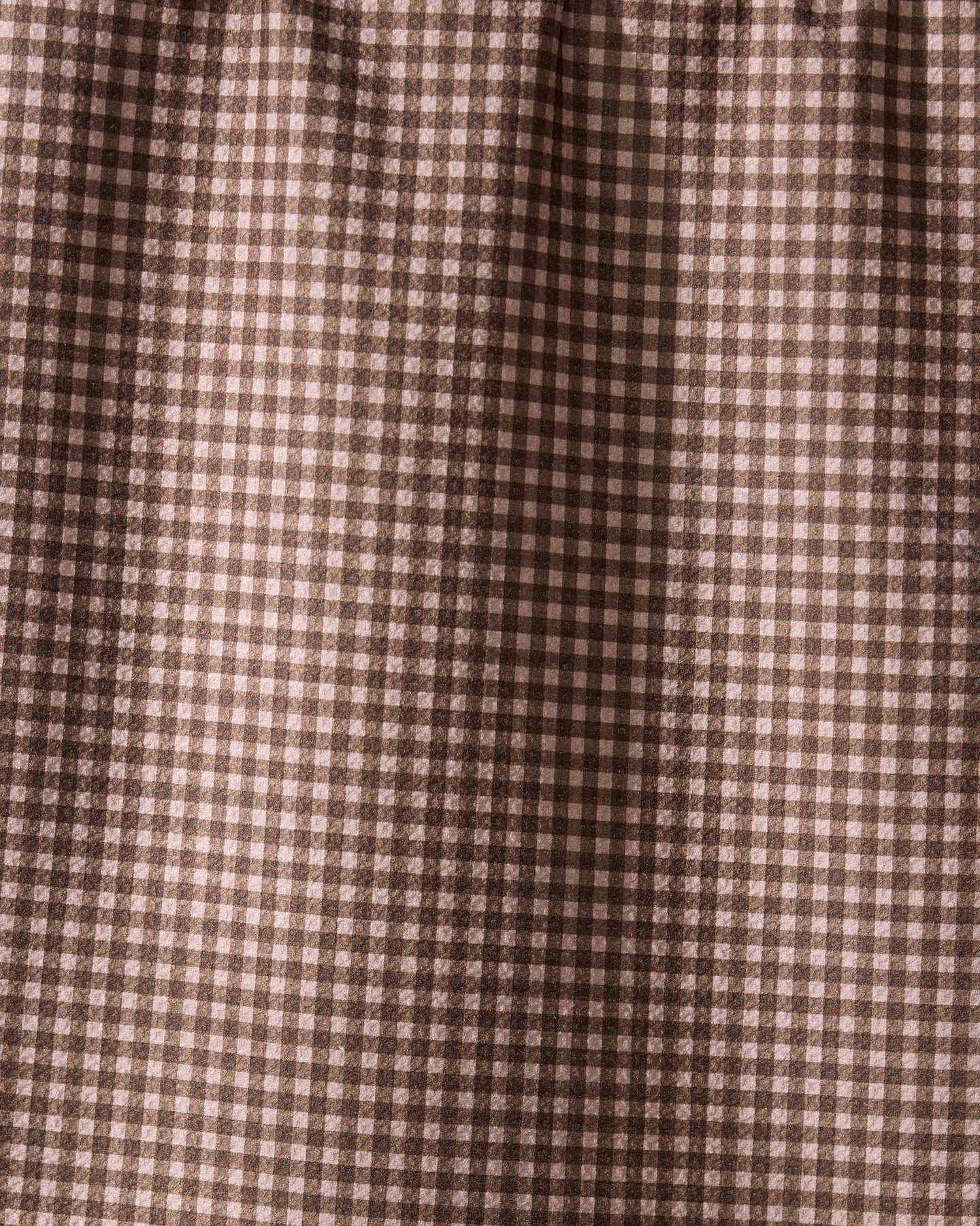Close-up of Hearth by Geometry, a recycled kitchen towel featuring a brown and cream gingham check with small squares in a repeating grid. The fabric is softly gathered at the top, highlighting its eco-friendly design.